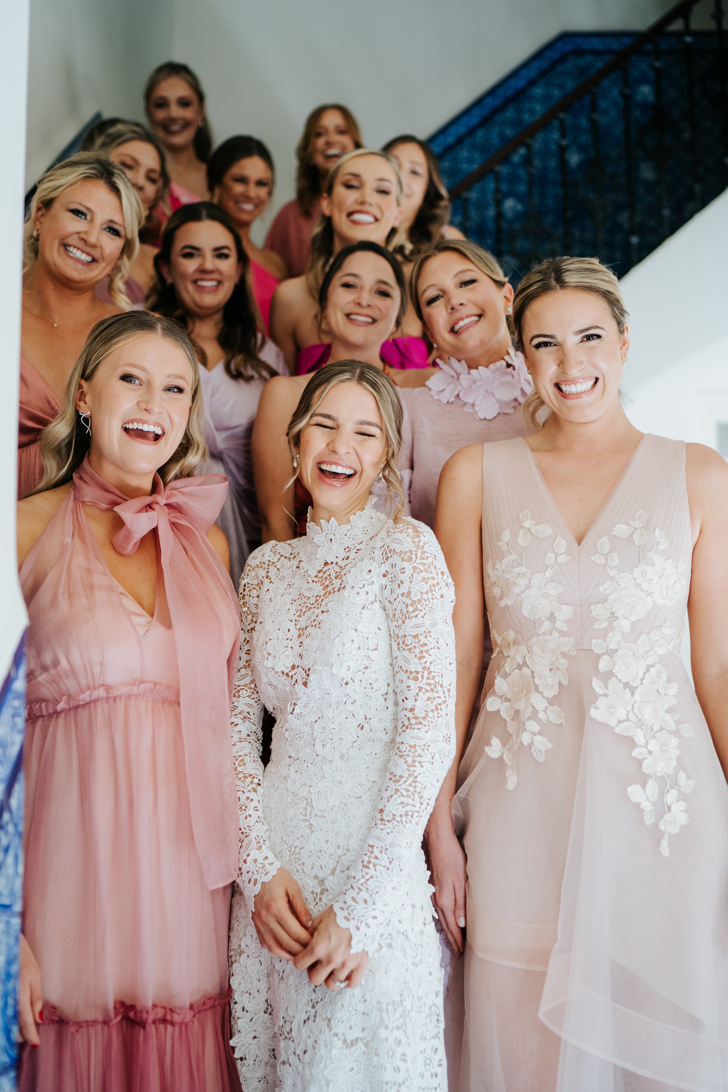 Group photograph of bride and 12 bridesmaids on staircase in Seville apartment
