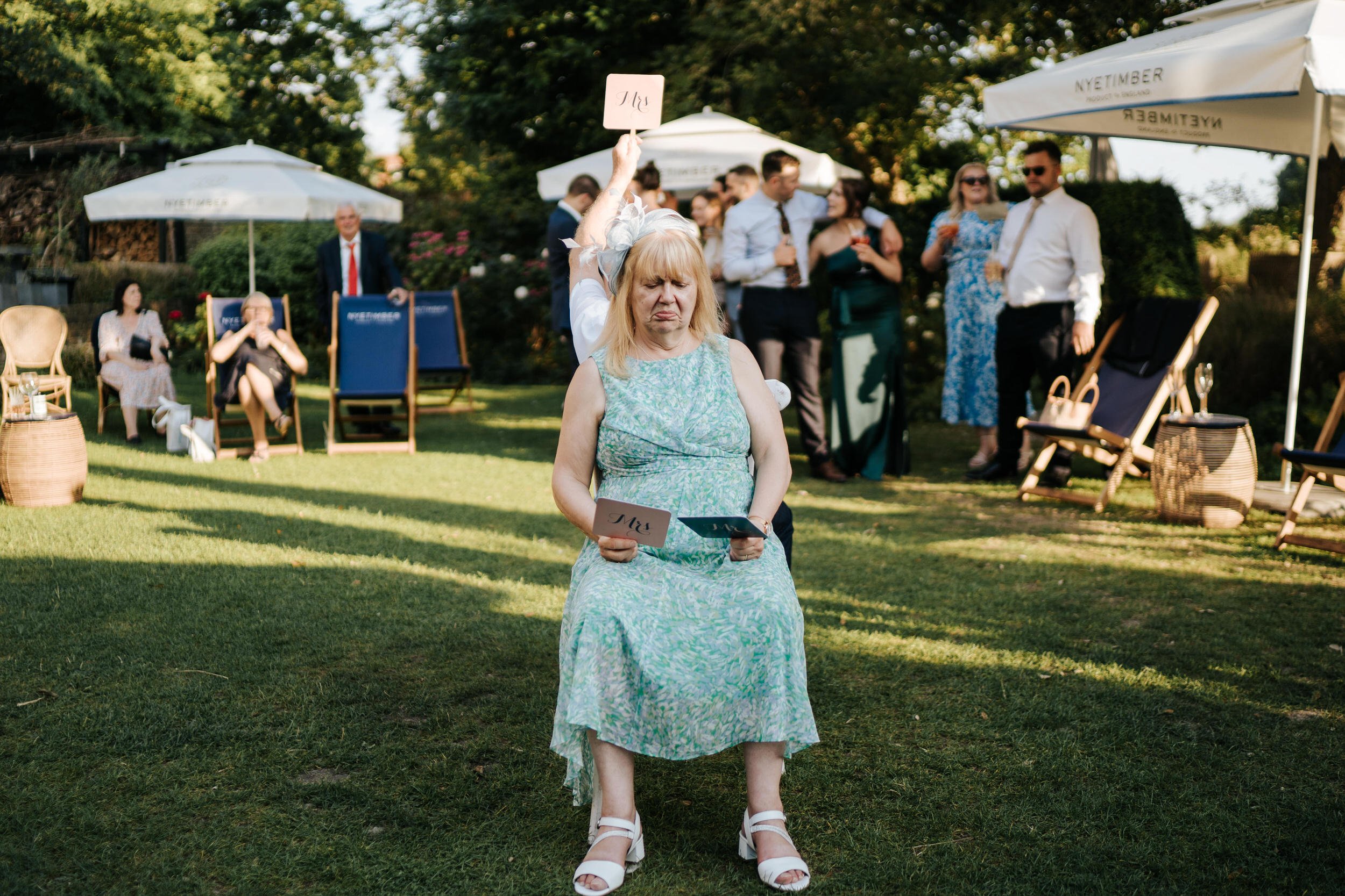 Mother of the bride looks with confusion at Mr & Mrs signs during game at Bingham Riverhouse