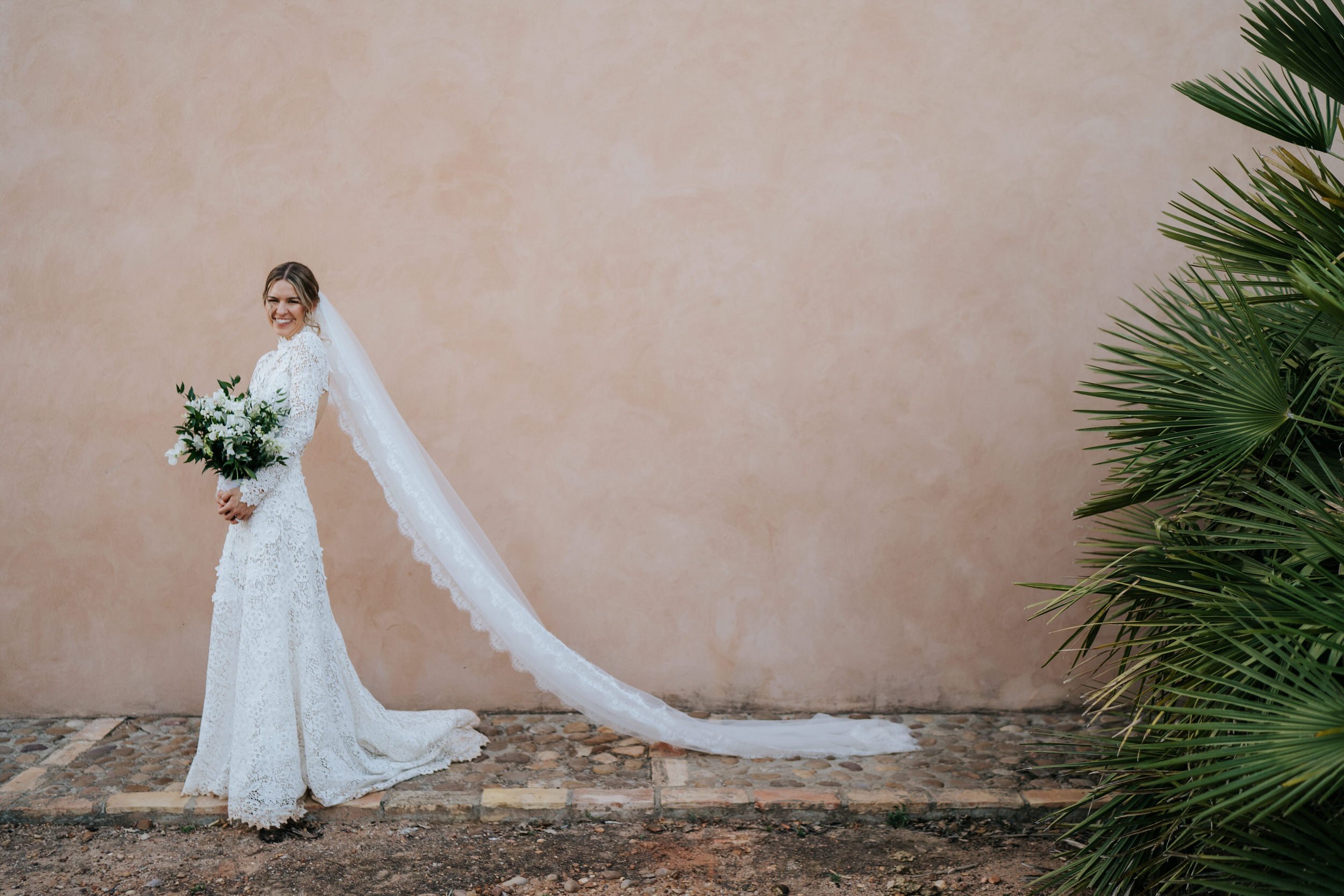 Bride poses gracefully with bouquet as mediterranean plant appears in frame off to her right
