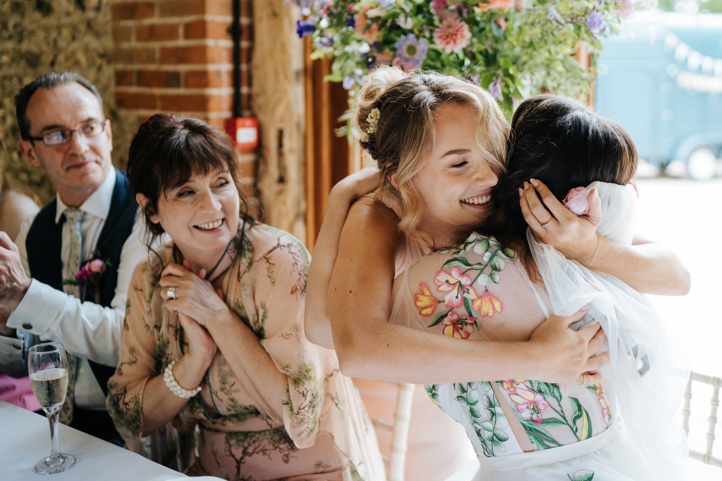 Bride's maid of honour hugs as her parents look from the side after emotional wedding speech