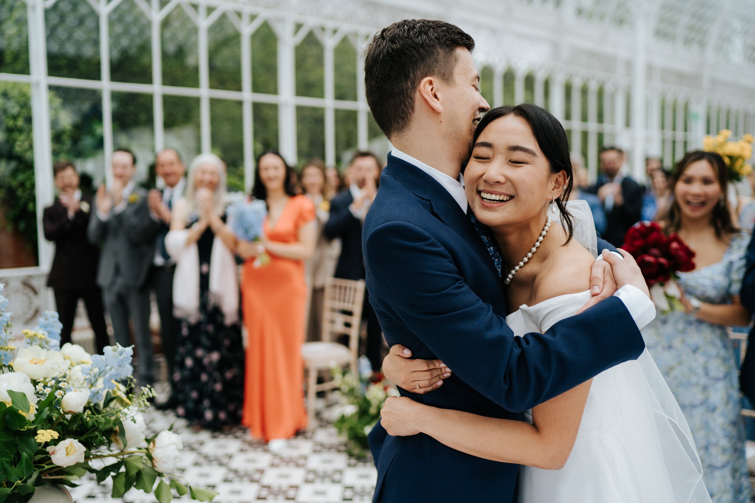 Bride and groom embrace after sharing first kiss during Horniman Conservatory wedding ceremony