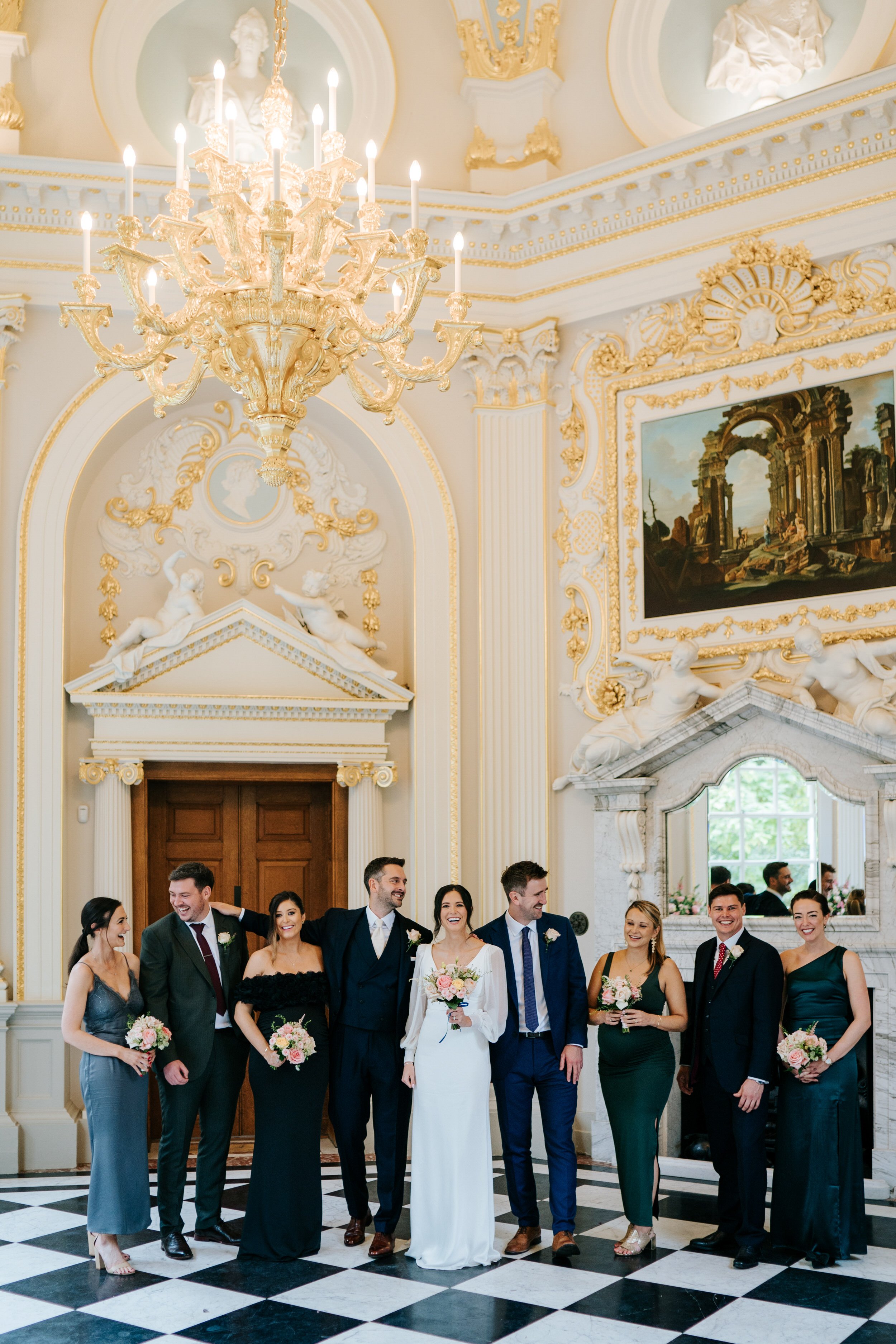 Elegant group photograph of bride, groom bridesmaids and groomsmen inside ornate Octagon Room at Orleans House Gallery