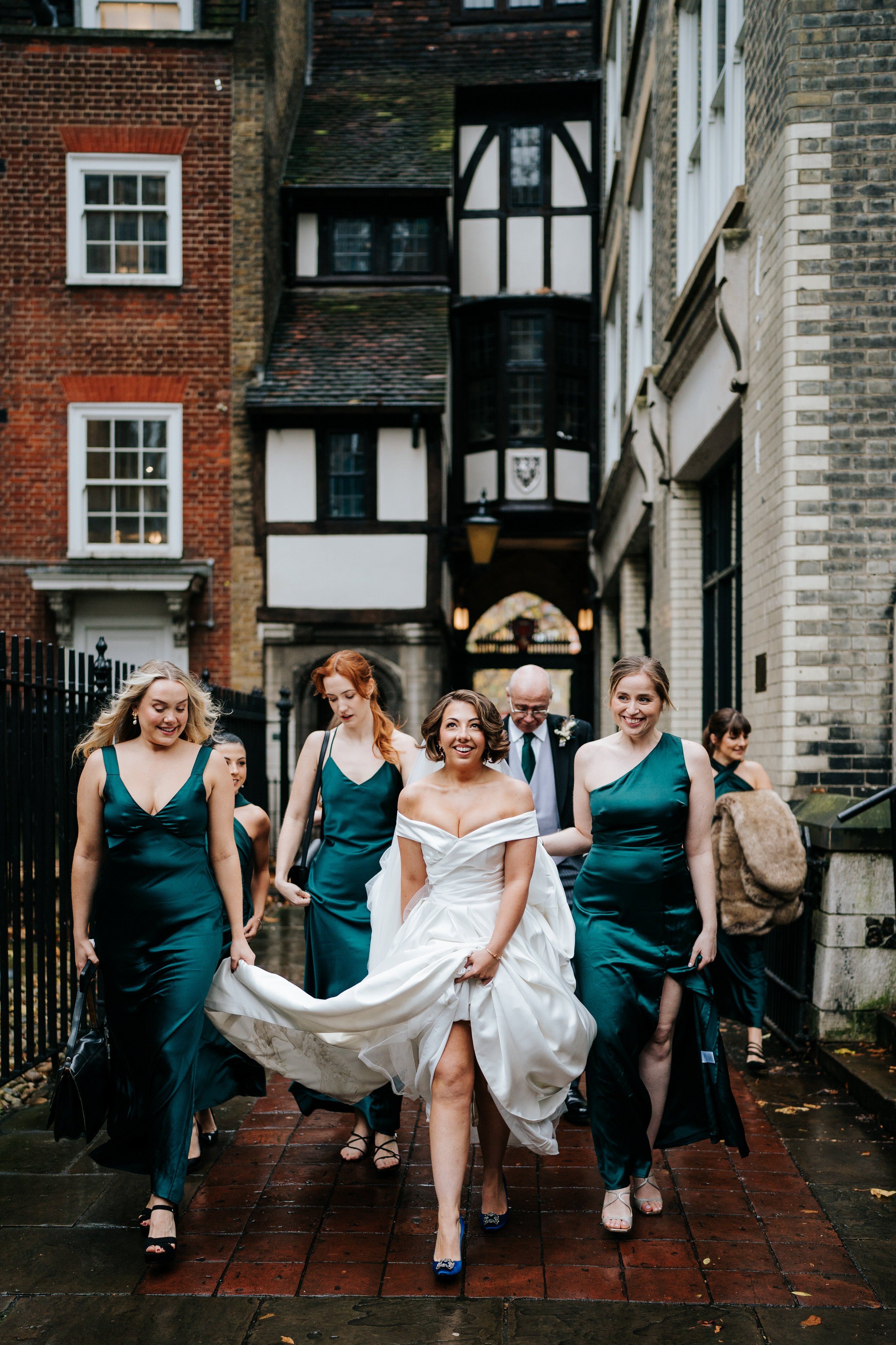 Bride and her entourage of bridesmaids walk towards church as bride looks up at the building in excitement and anticipation