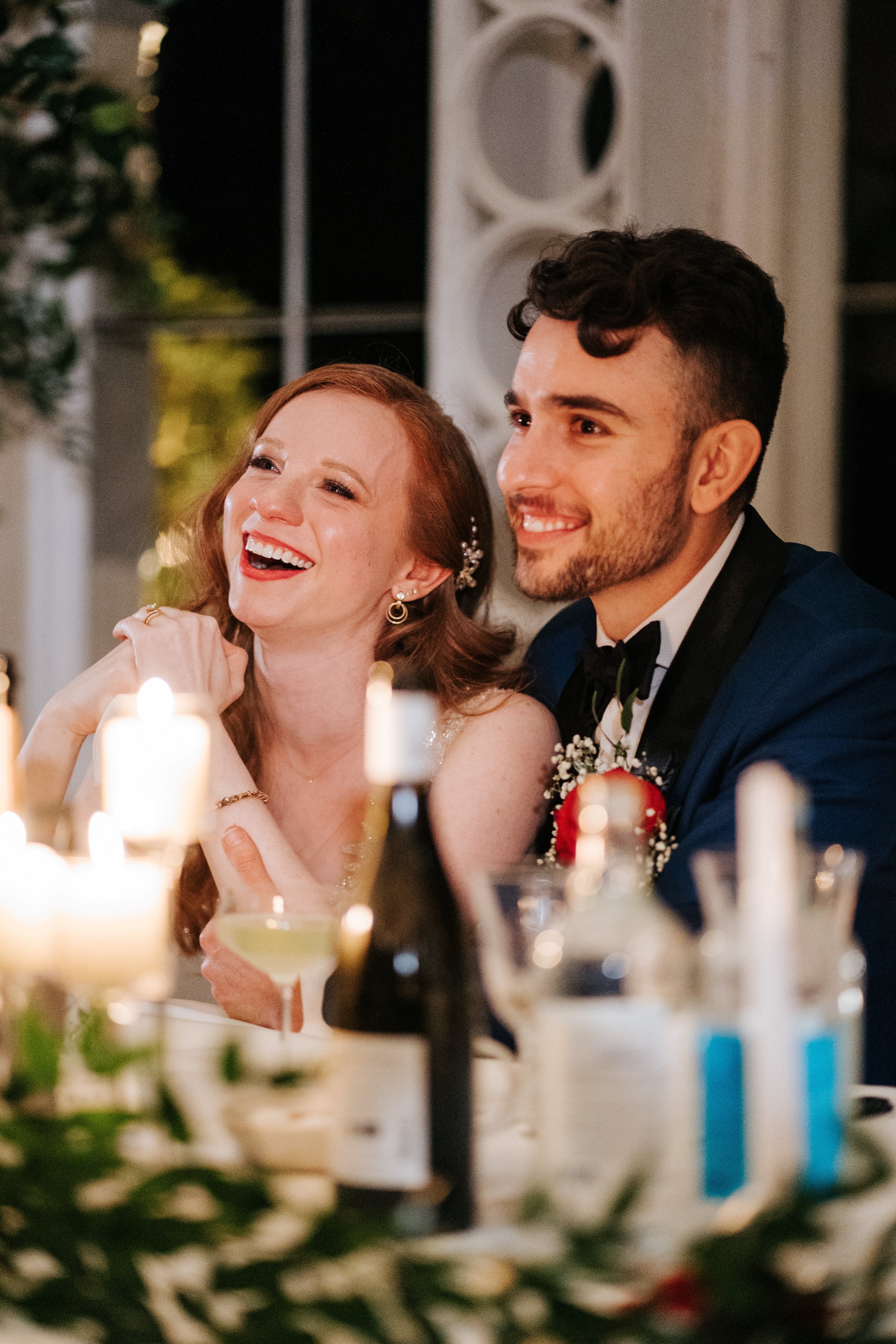 Close-up of bride and groom laughing as they listen to wedding speeches at Syon Park