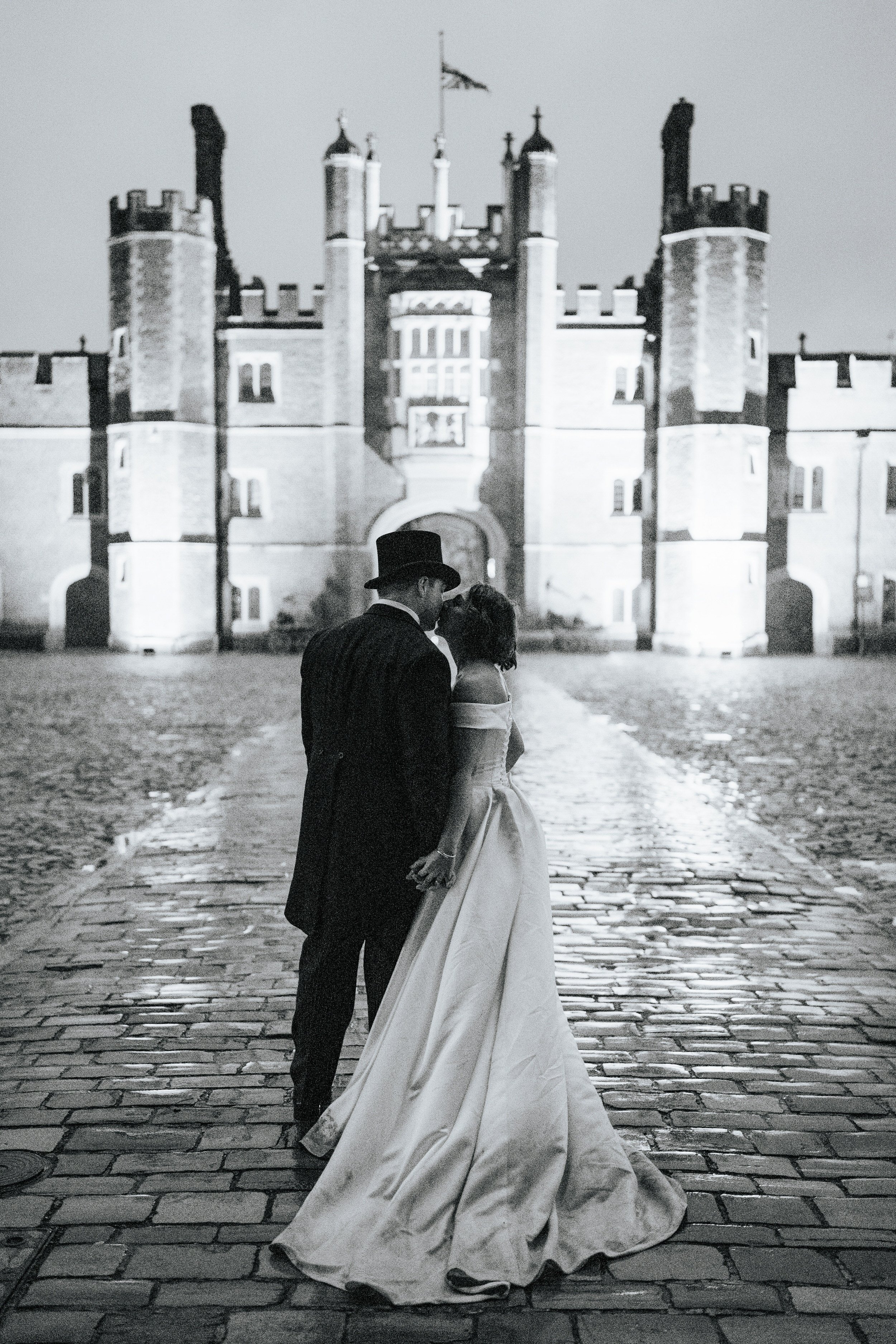 Moody black and white photograph of bride and groom in courtyard at Hampton Court Palace