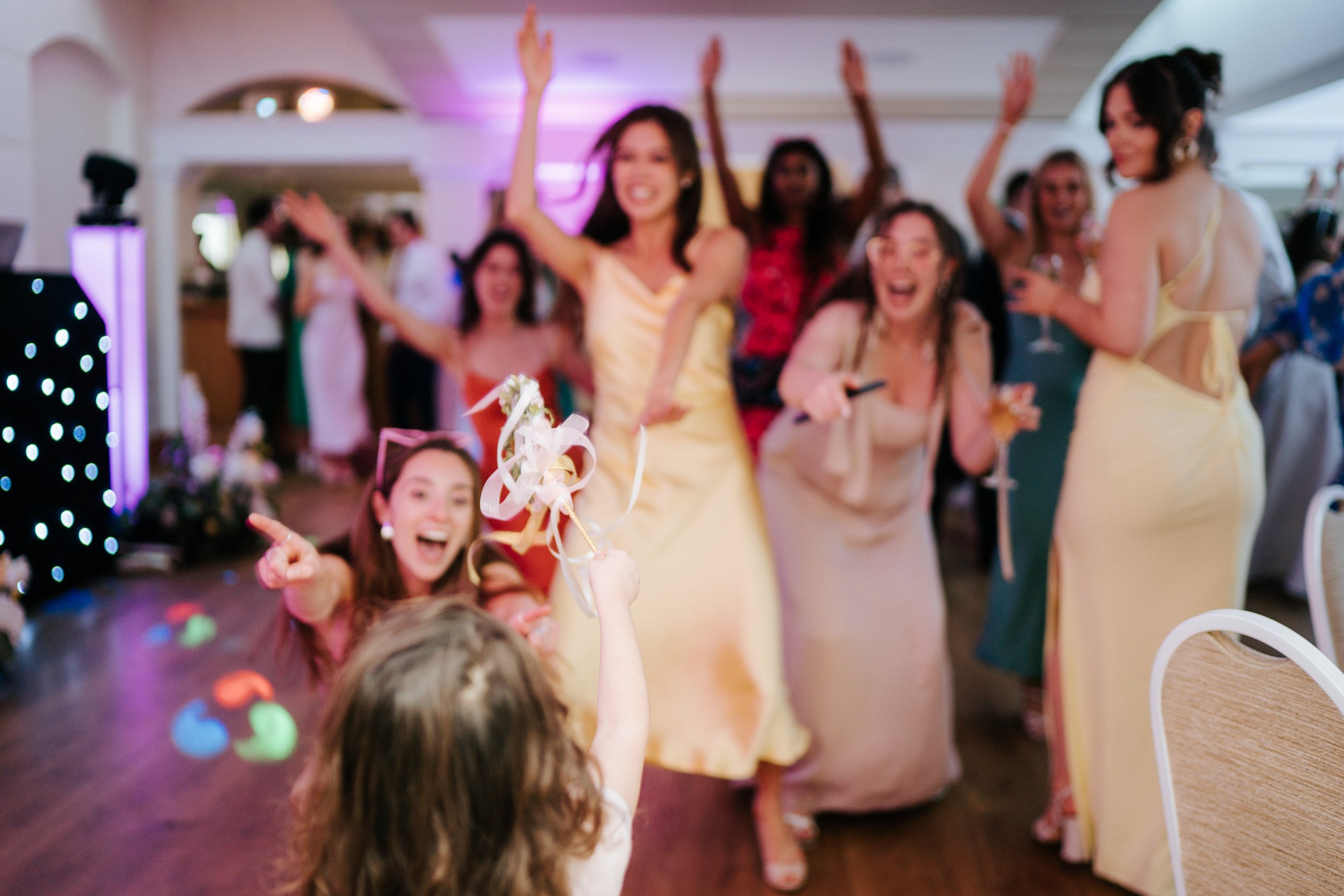 Little girl uses wand on group of women dancing in front of her at Pembroke Lodge wedding