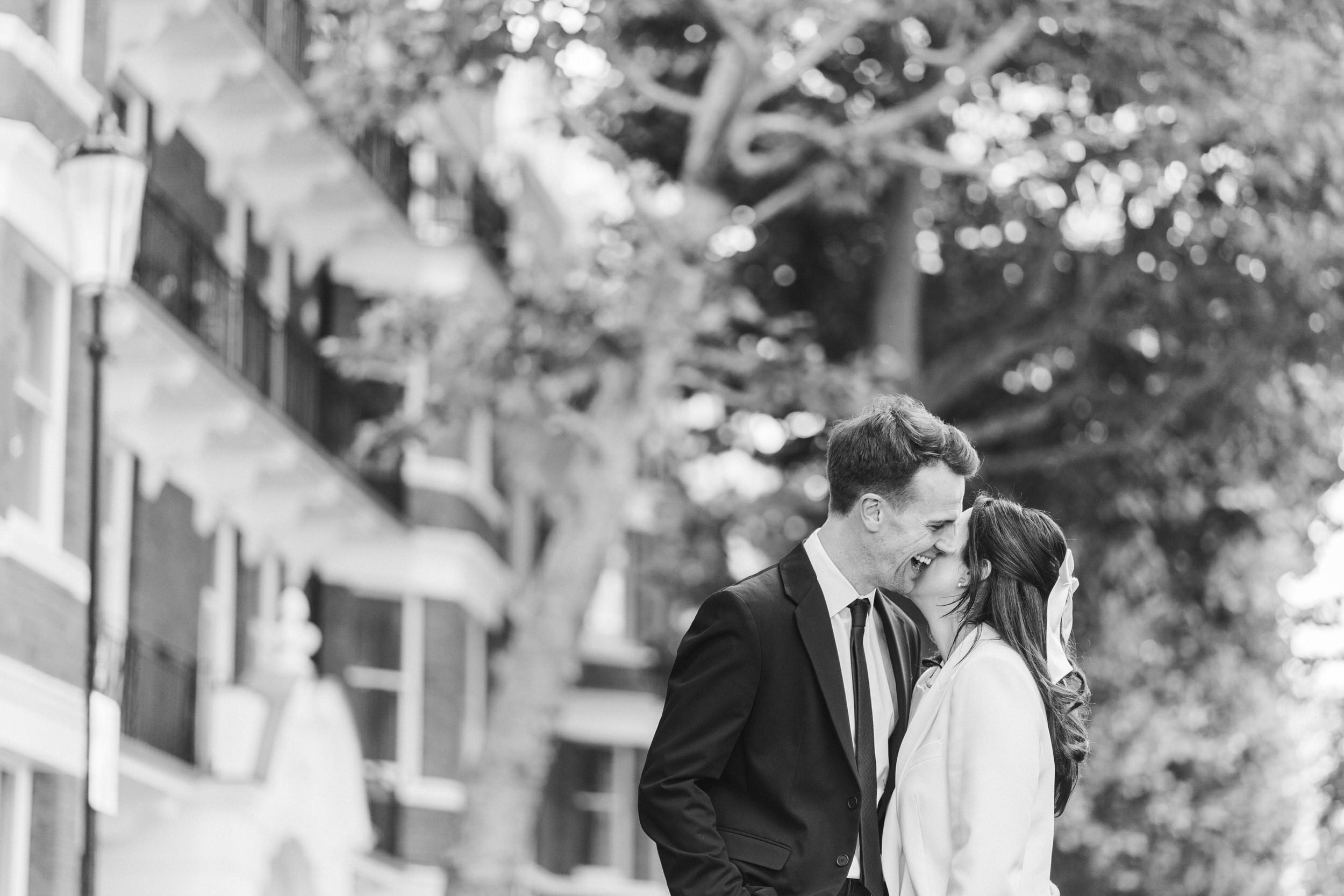 Black and white photograph of groom smiling as he embraces bride