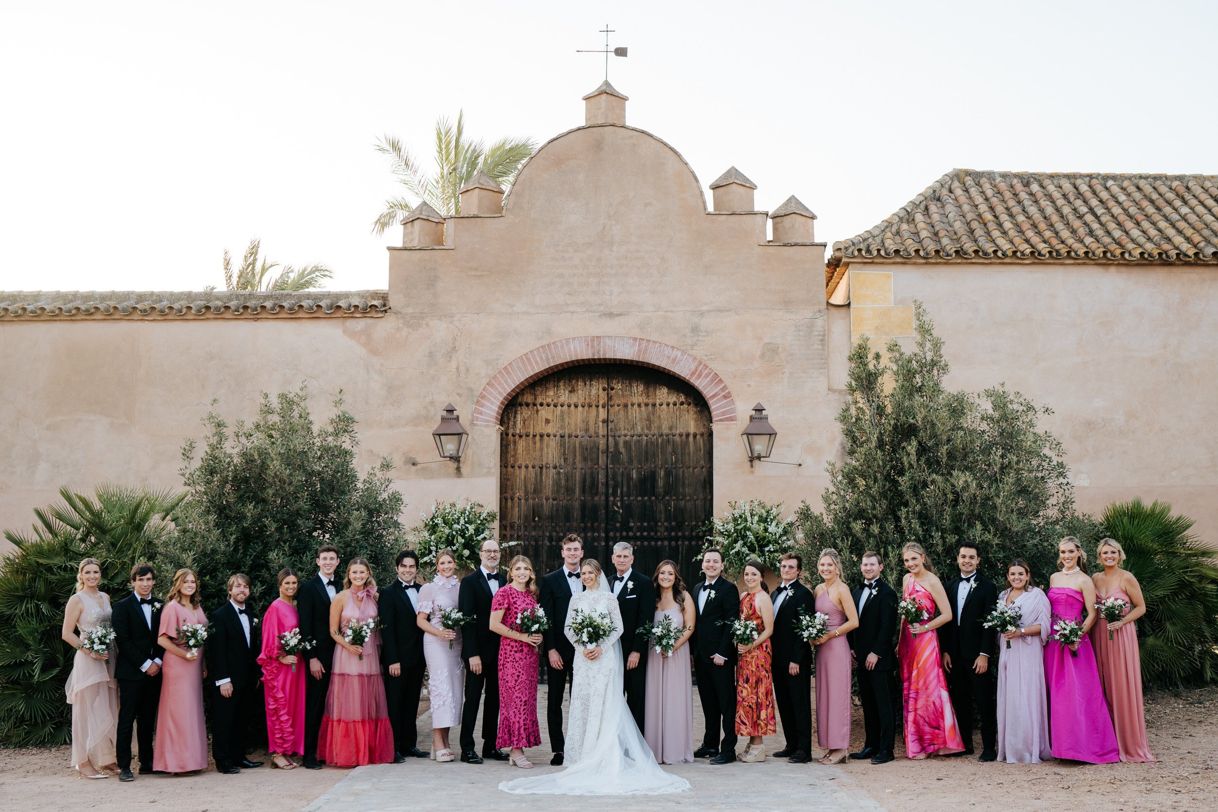 Elegant photograph of bridal party posing in front of beautiful gate in Seville wedding