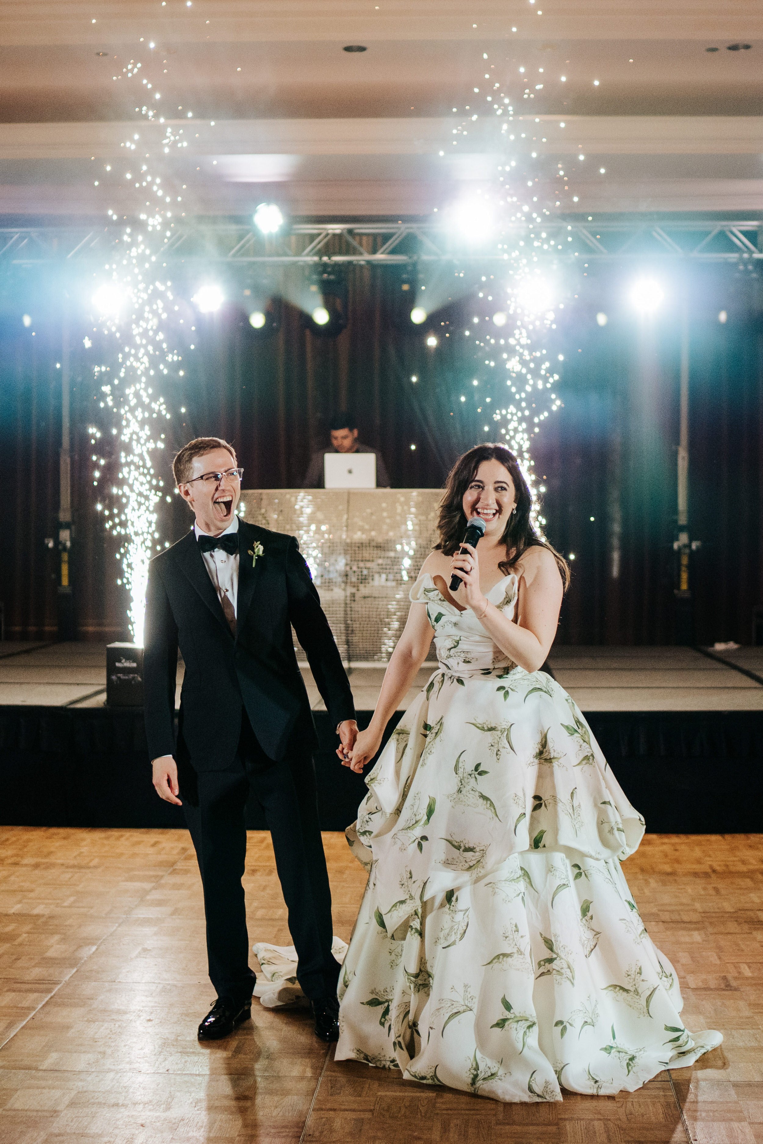 Bride and groom stand on dancefloor and thank all of their guests as sparkler cannons go off behind them