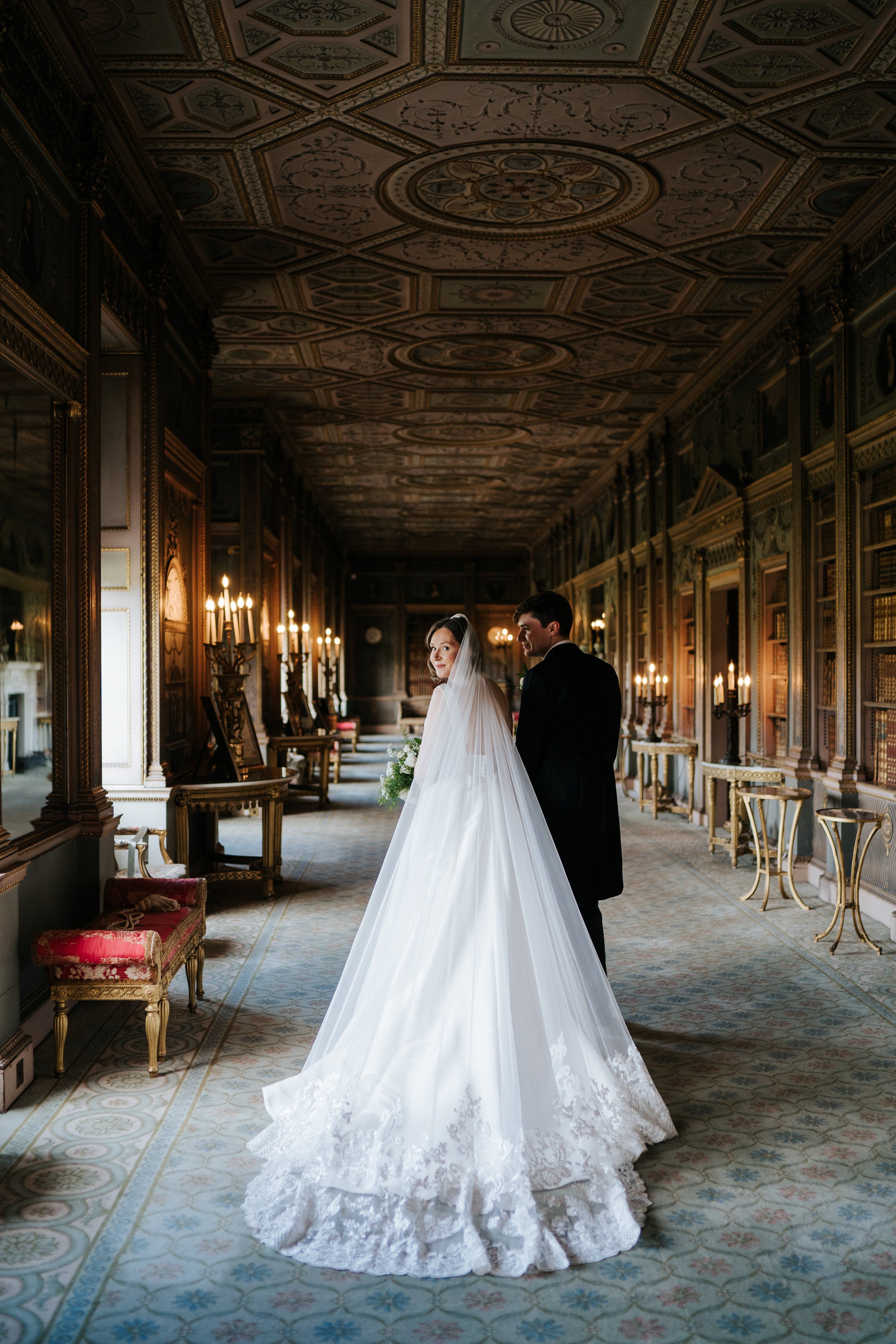 Bride and groom walk away from camera in gallery room at Syon Park in elegant couple photograph