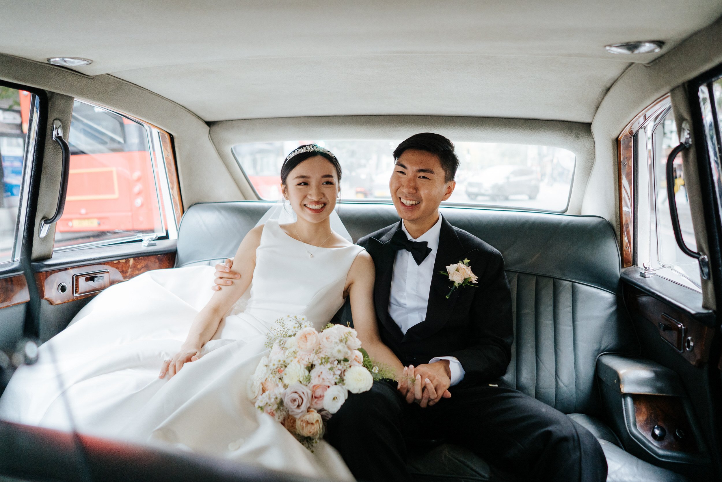 Bride and groom sit in back of car after wedding ceremony