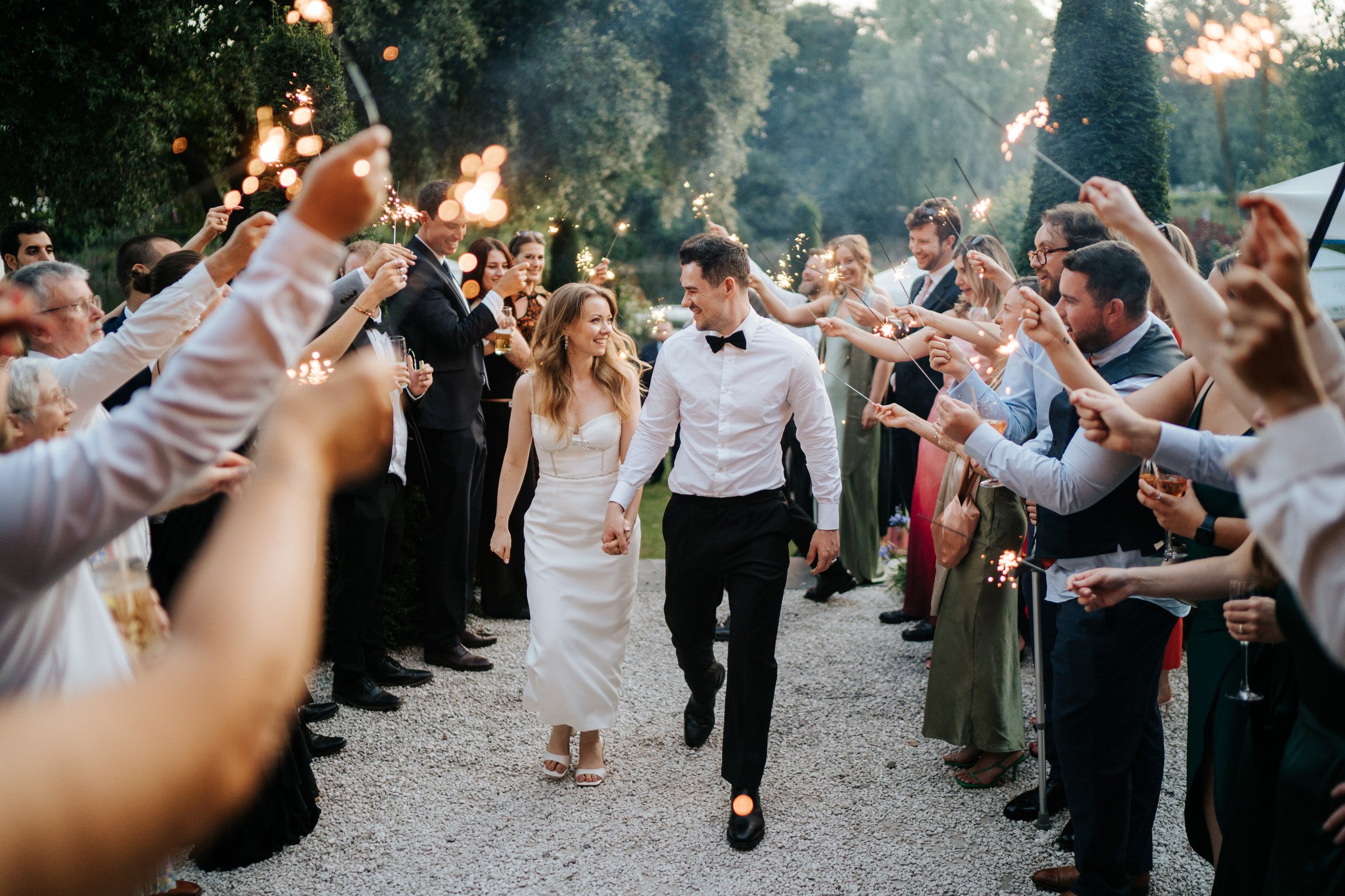 Bride and groom look at each other as they walk through confetti tunnel at Bingham Riverhouse wedding