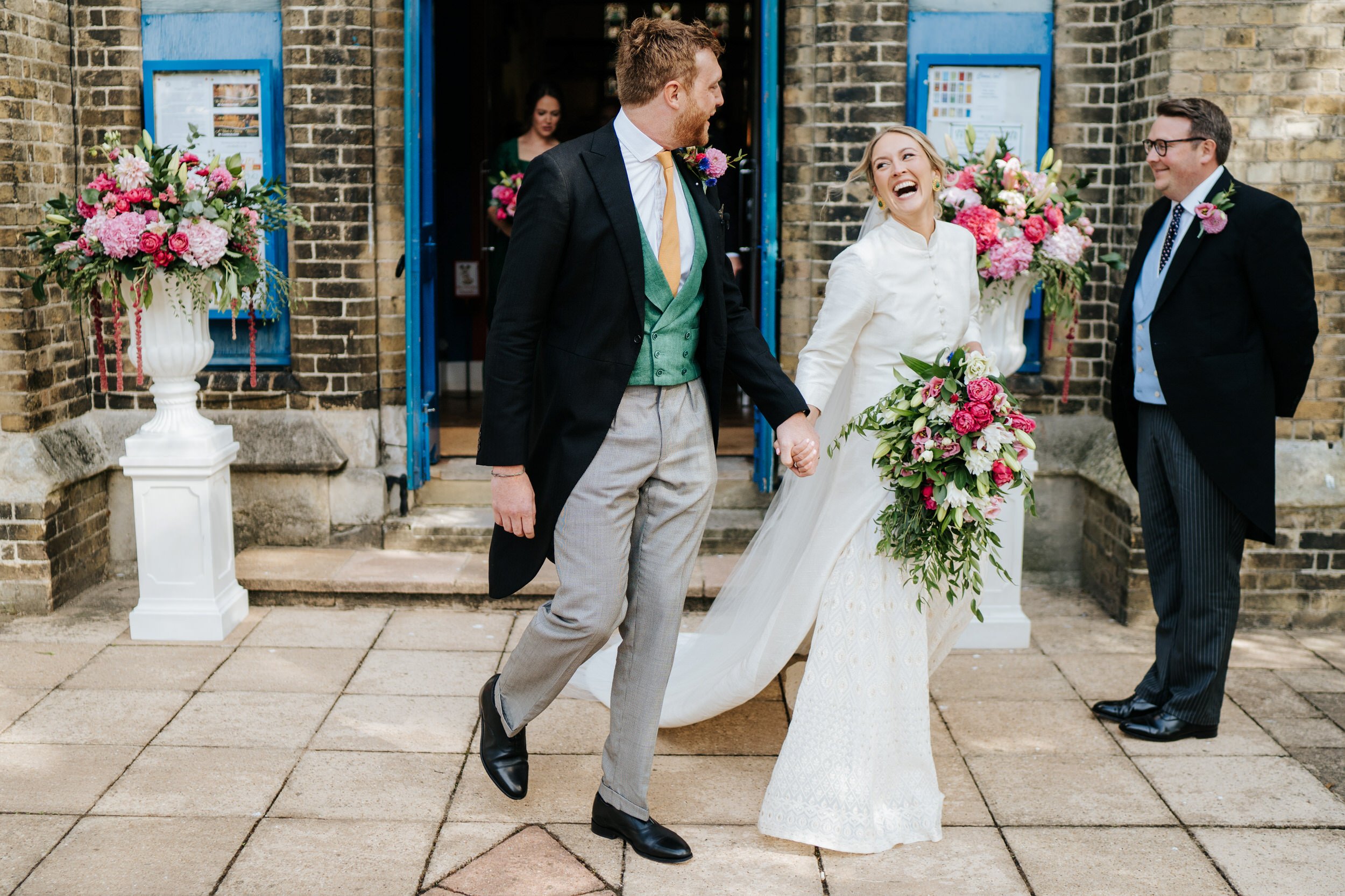 Bride and groom exit church in Windsor as bride smiles from ear to ear and looks at groom