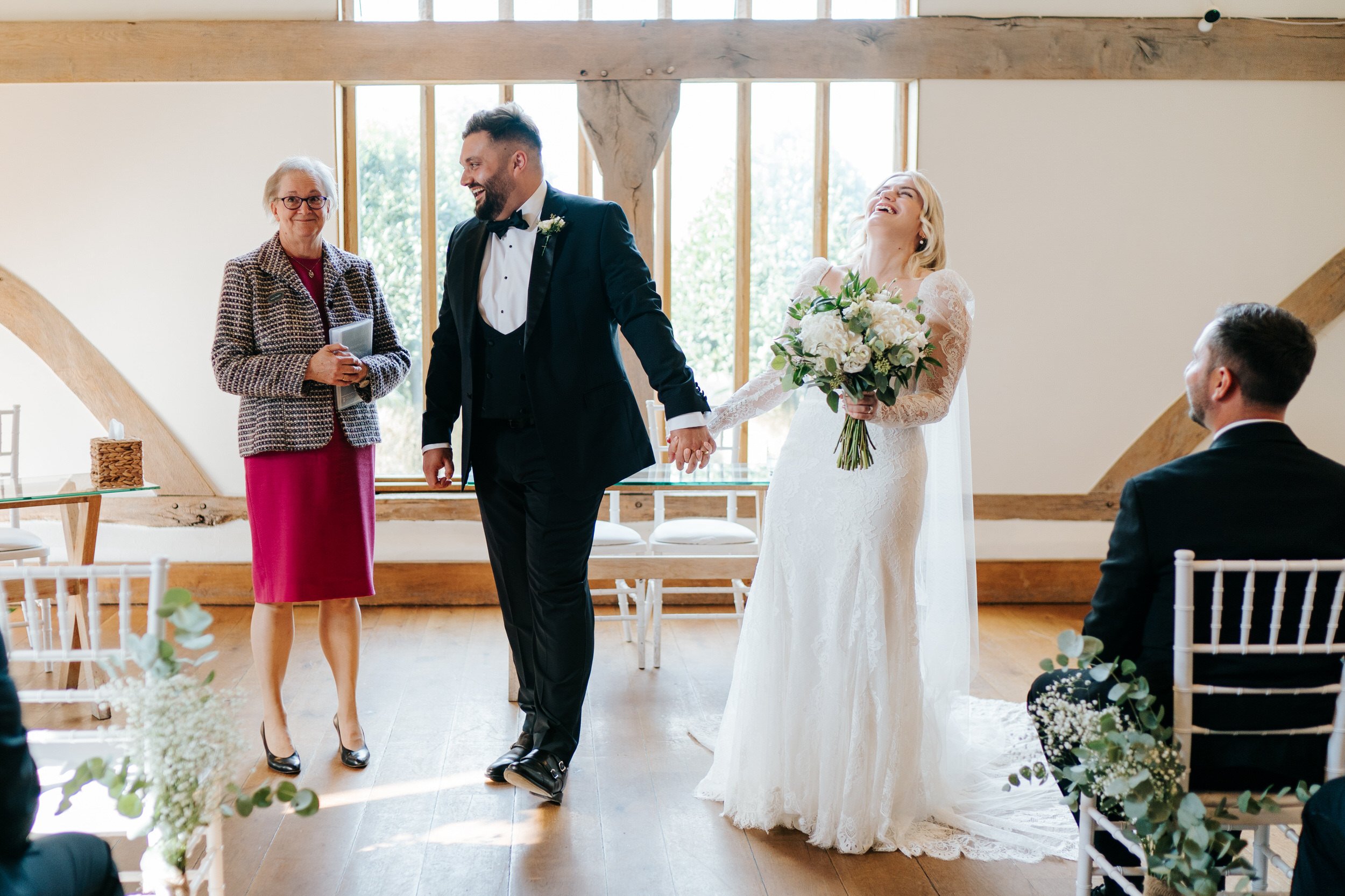 Bride and groom get ready to walk back down the aisle after civil ceremony as registrar looks at them in embarrassment after forgetting bride's name
