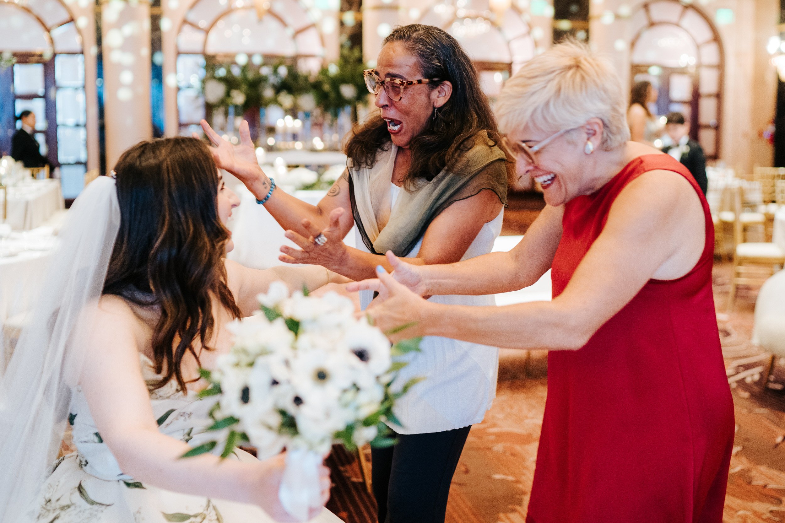 Two family members approach bride in gleeful excitement
