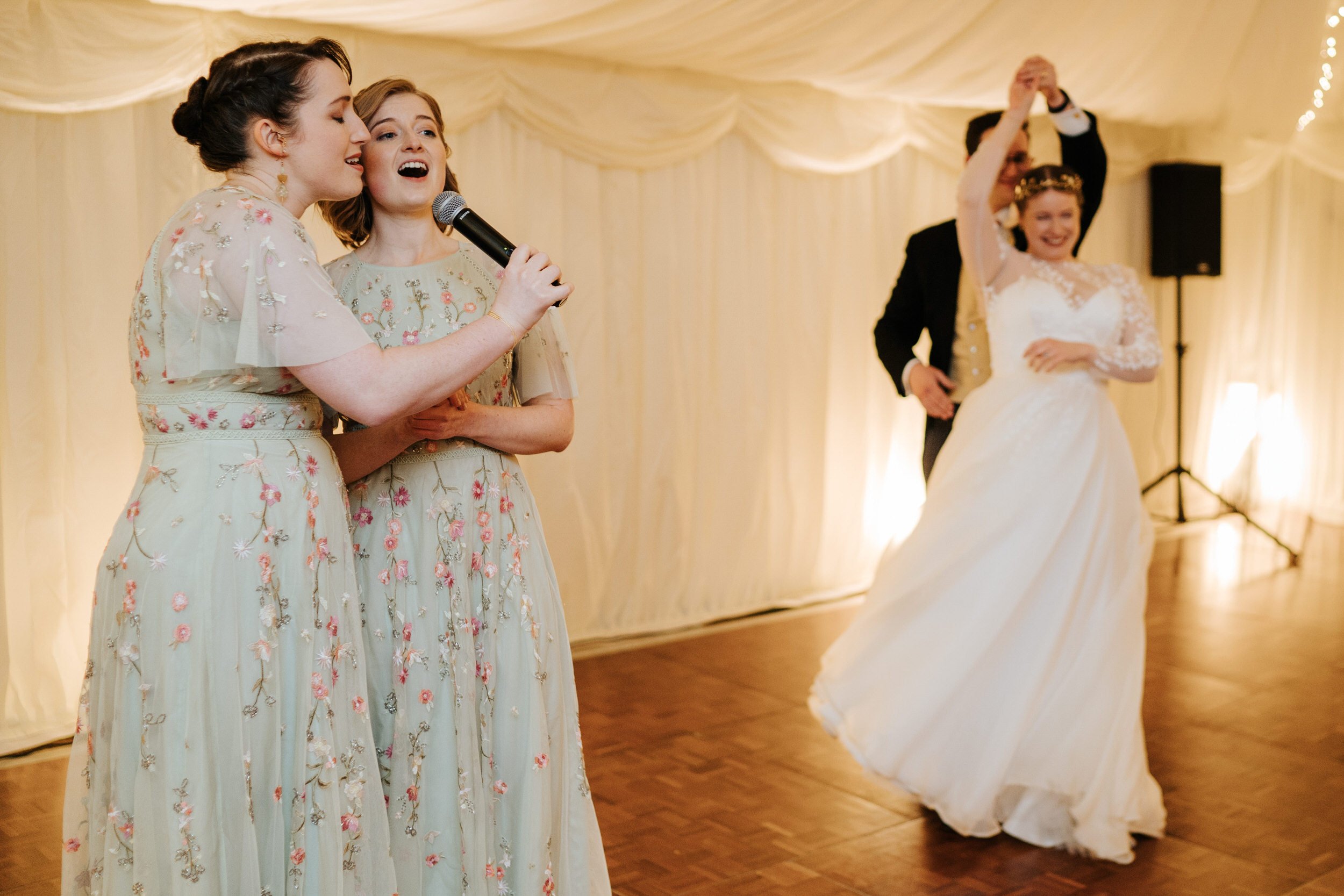 Two bridesmaids sing as bride and groom share first dance at Hampton Court Palace wedding