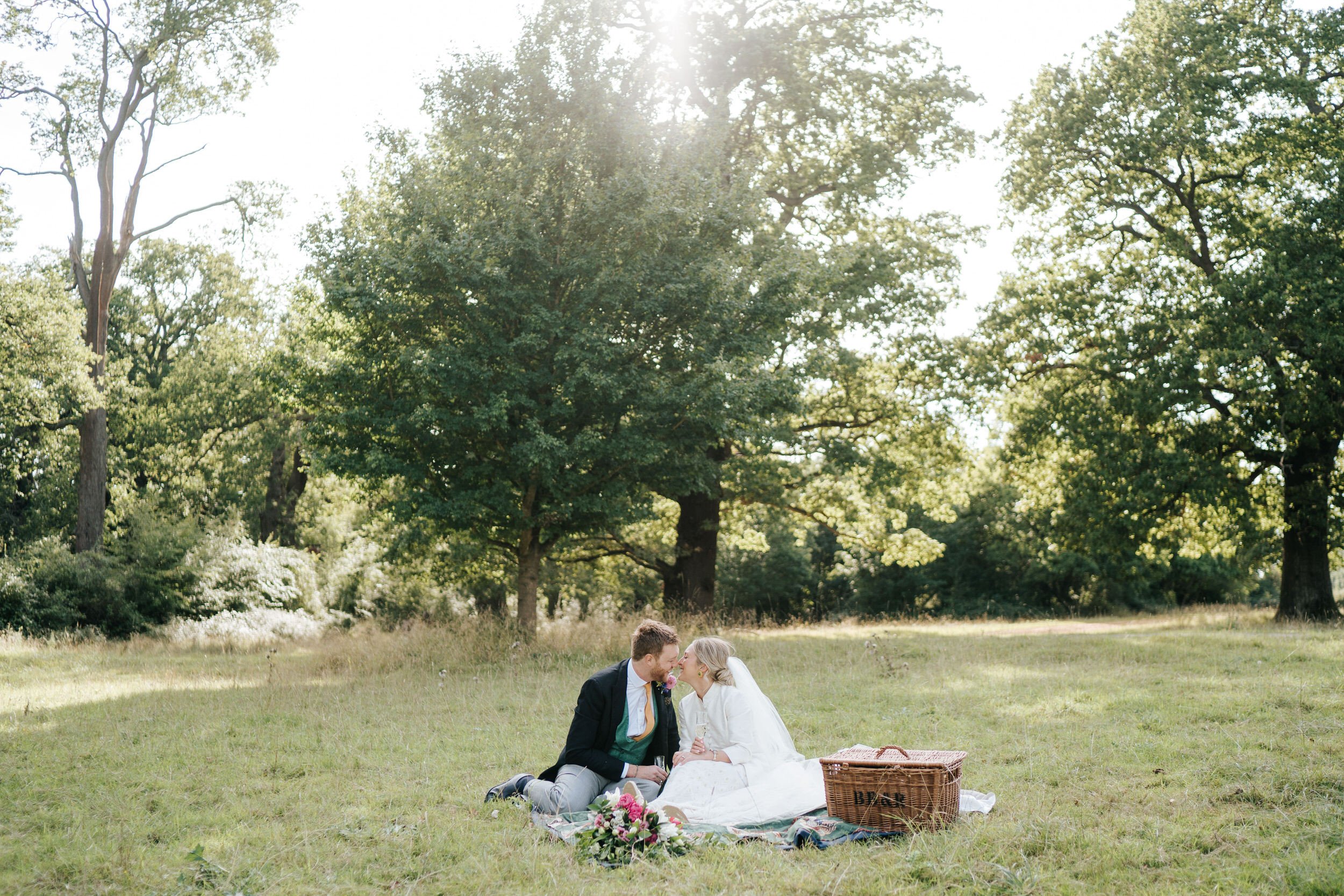Wide photograph of bride and groom sharing a picnic after their wedding ceremony in Windsor