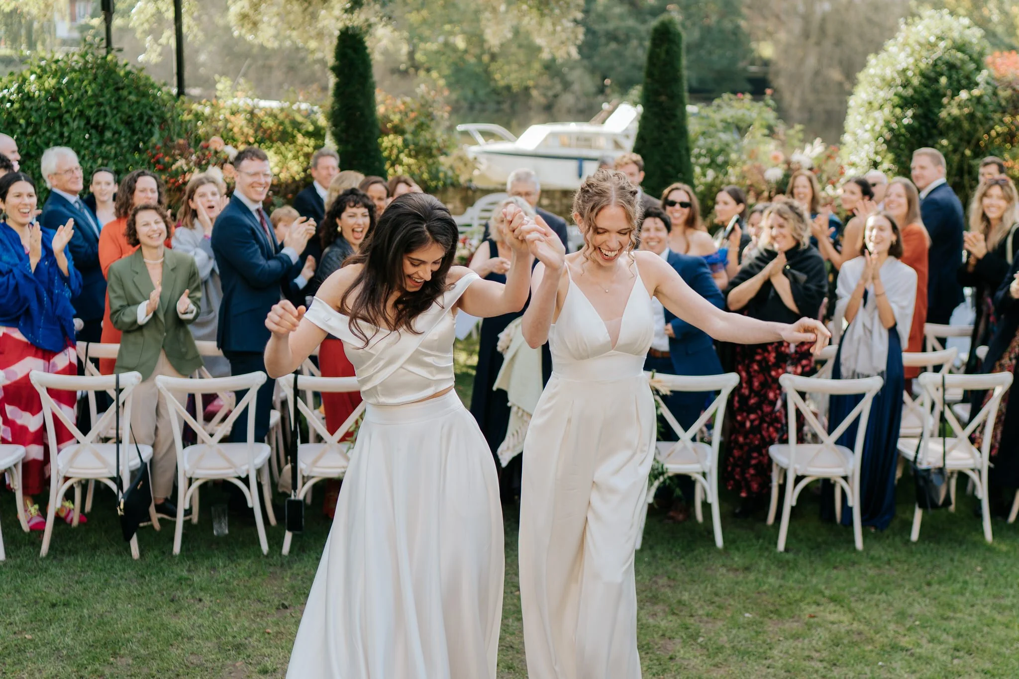 Two brides cannot contain their joy as they walk back down the aisle at Bingham Riverhouse outdoor ceremony