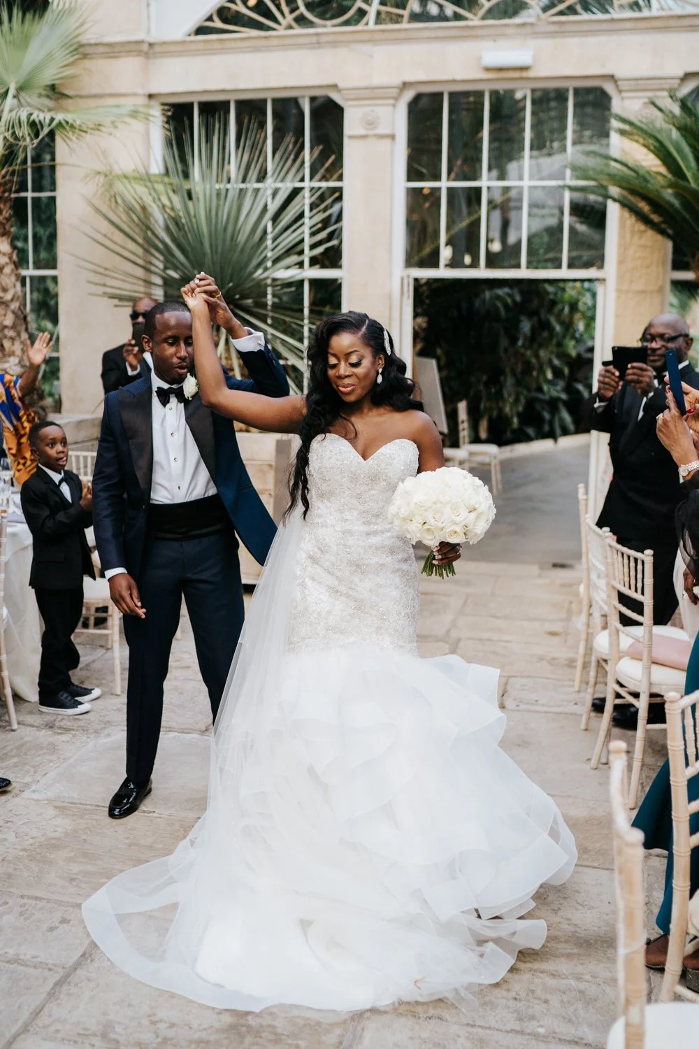 Bride and groom enter the great conservatory at Syon Park while groom twirls bride