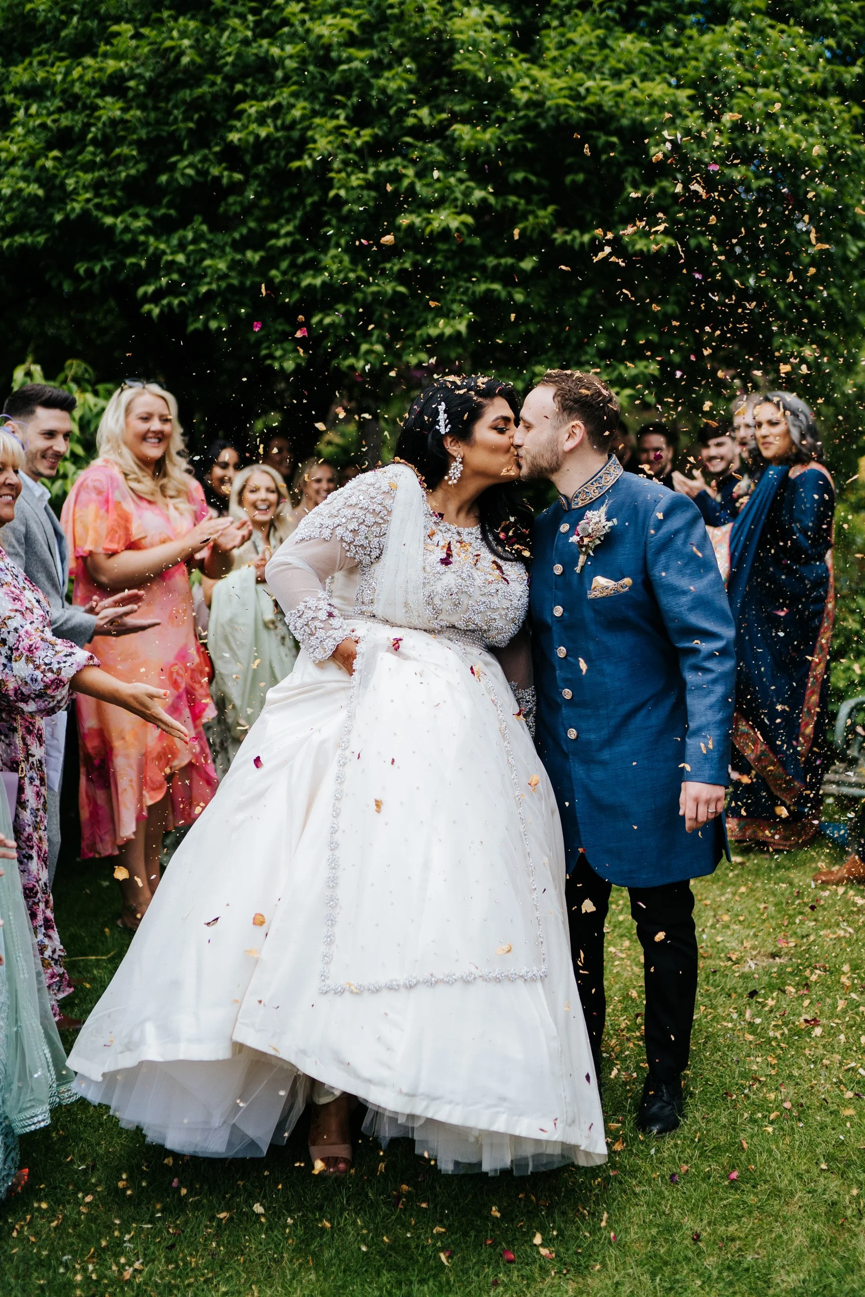 Bride and groom walk down confetti tunnel in multicultural Walcot Hall wedding
