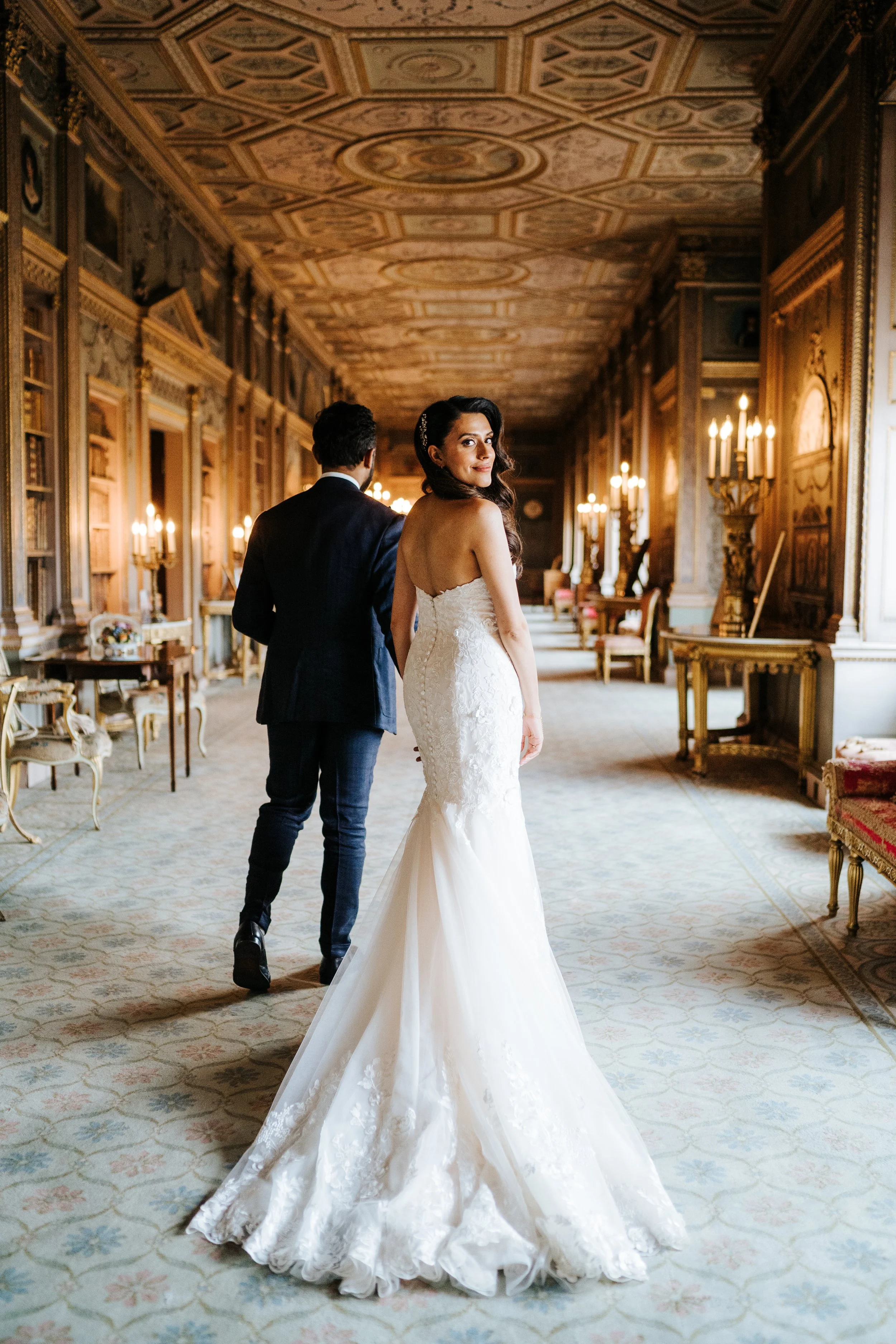 Bride and groom walk down ornate room at Syon House wedding