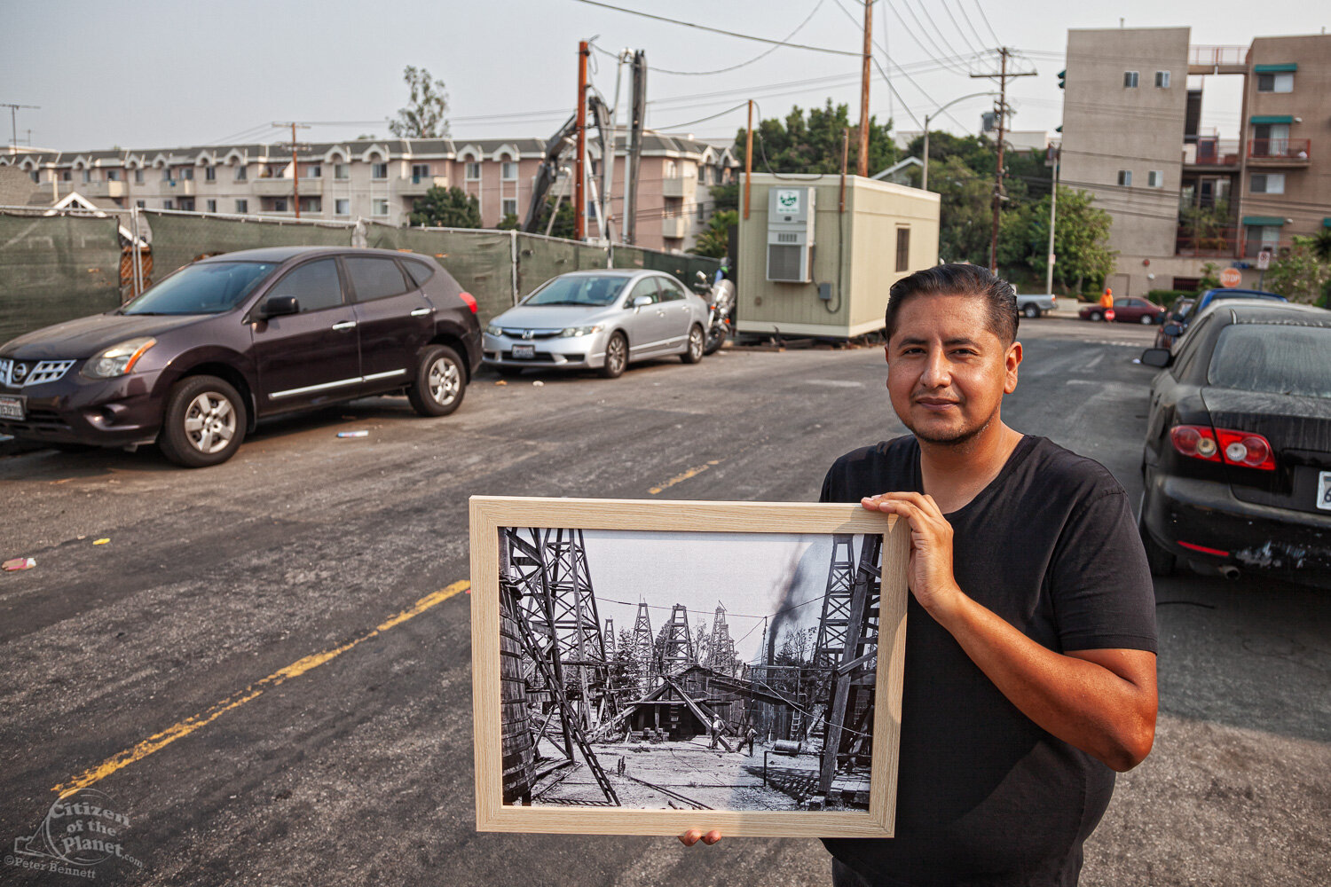  Resident and neighborhood activist, Danny Luna holds a photo from 1904 of the intersection of Toluca and Court Street – an area once dotted with oil derricks. Today, it is the location of a 120-unit development by Aragon Holdings.  