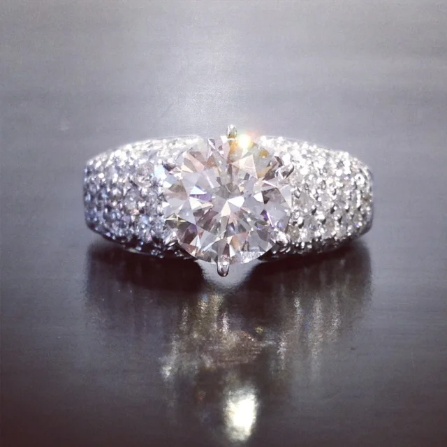  Domed, pave diamond ring in 18k w.g. with 1.50 ct., round brilliant cut center. 