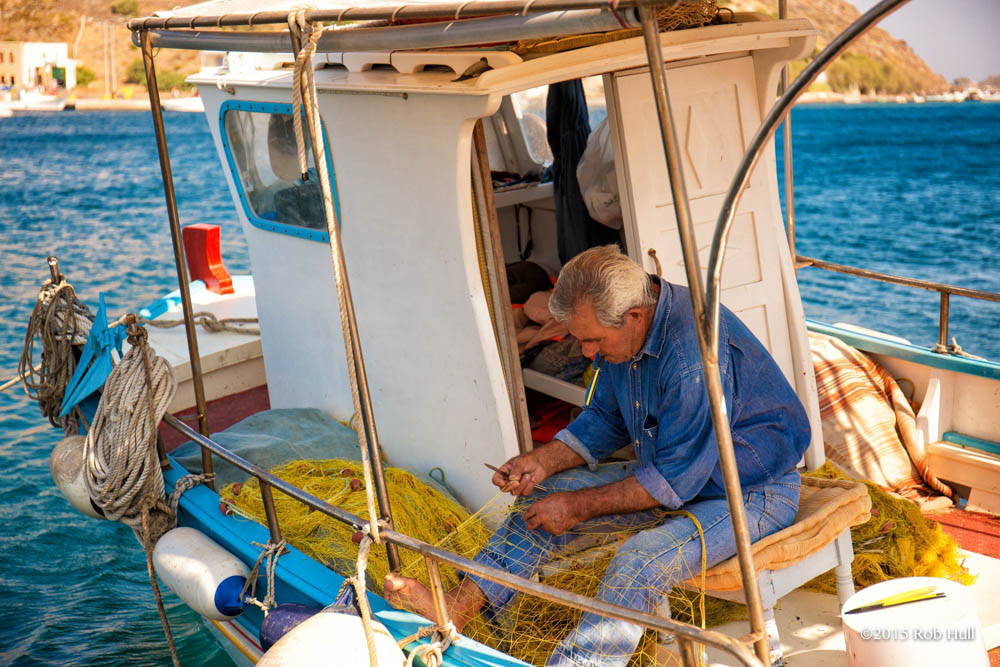 Fisherman in Patmos, Greece, tends to his fishing nets.