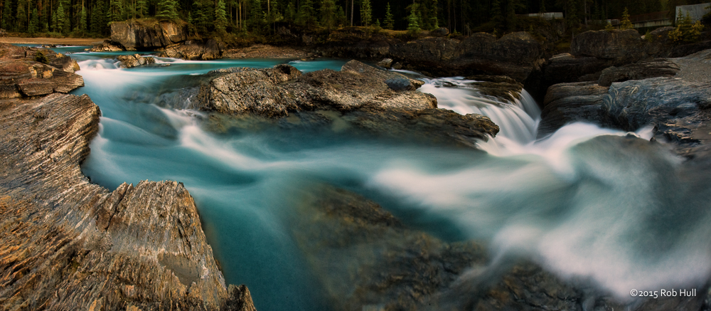 The azure blue water from the Kicking Horse River tumbles down the canyon and undercuts the Natural Bridge rock formation in Canada’s Yoho National Park.