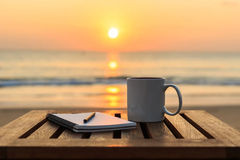 47639945 - close up coffee cup on wood table at sunset or sunrise beach