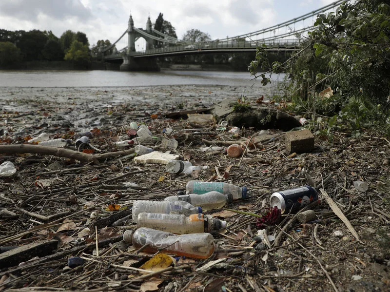 Single-use plastic bottles lie washed up on the bank of the River Thames by the Queen Caroline Draw Dock in London. Image via Matt Dunham/AP