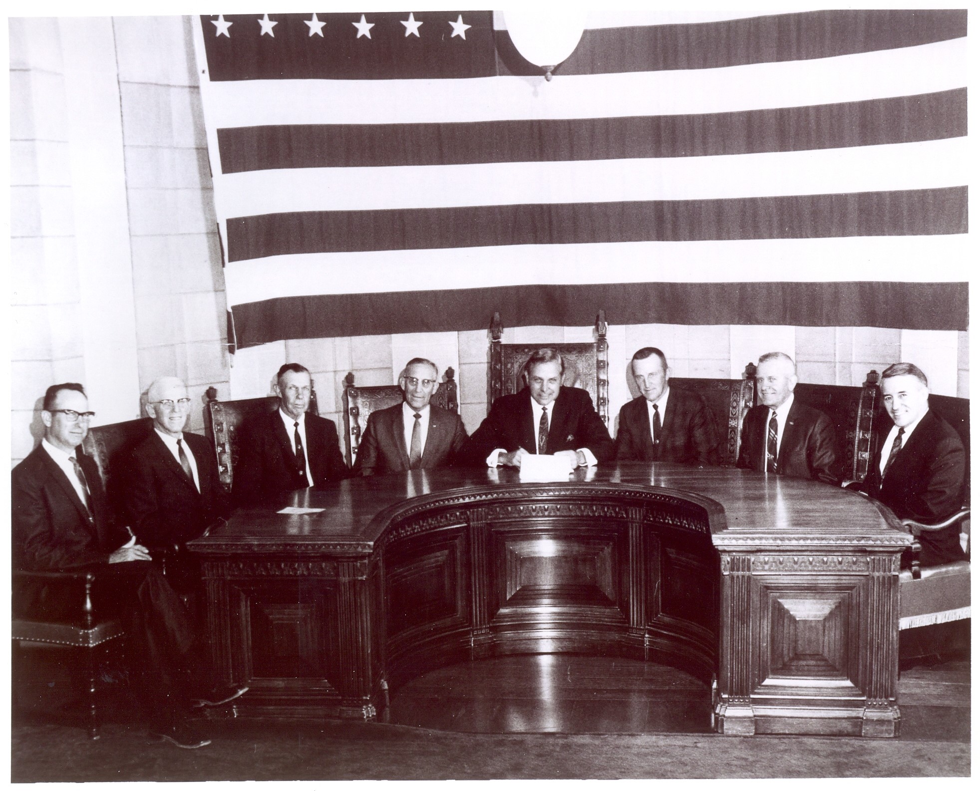 The signing of the bill to create NRDs in Nebraska in 1972 - Those instrumental in the bill's passage were, from left: Harold Siek, Herman Link, Chet Ellis, Senator Maurice Kremer, Governor Norbert Thiemann, Warren Patefield, Milton Fricke, and Warren Fairchild. Nebraska's NRDs began when the legislature consolidated 154 watershed districts and conservation districts into 24 local watershed-based Natural Resources Districts.