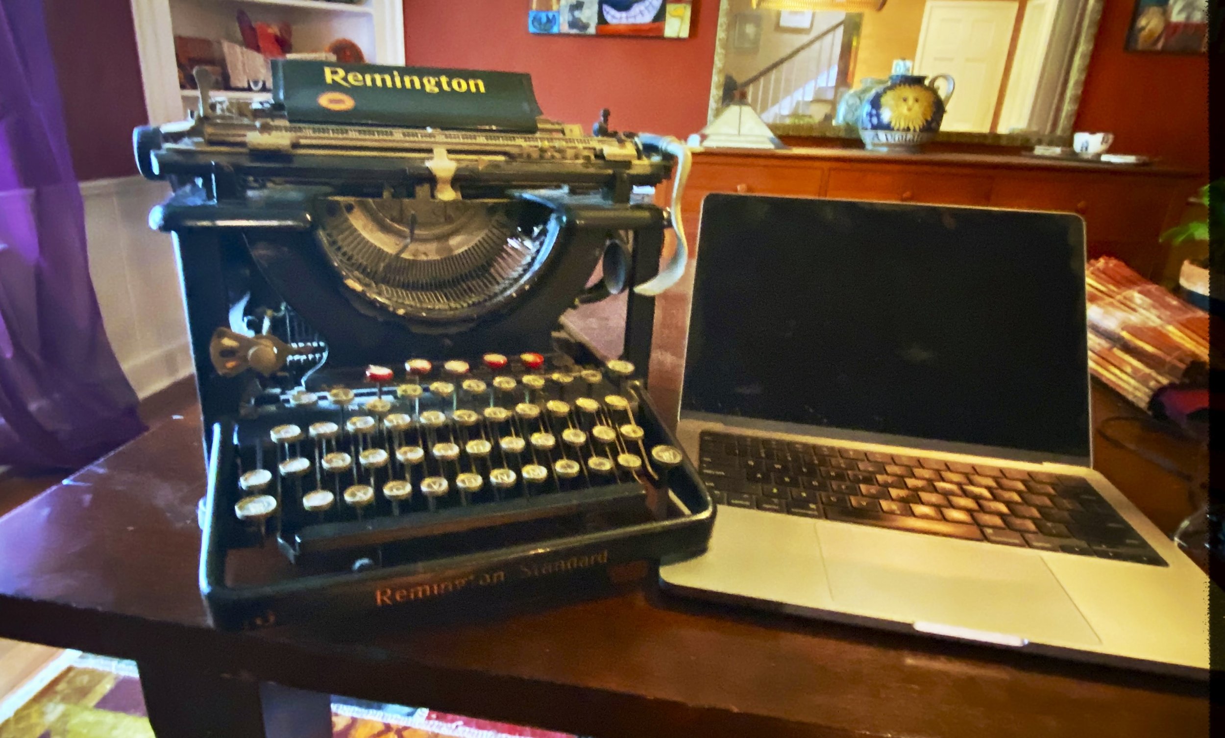 An artful, out-of-focus image of an old Remington typewriter sitting side by side with a modern Apple laptop