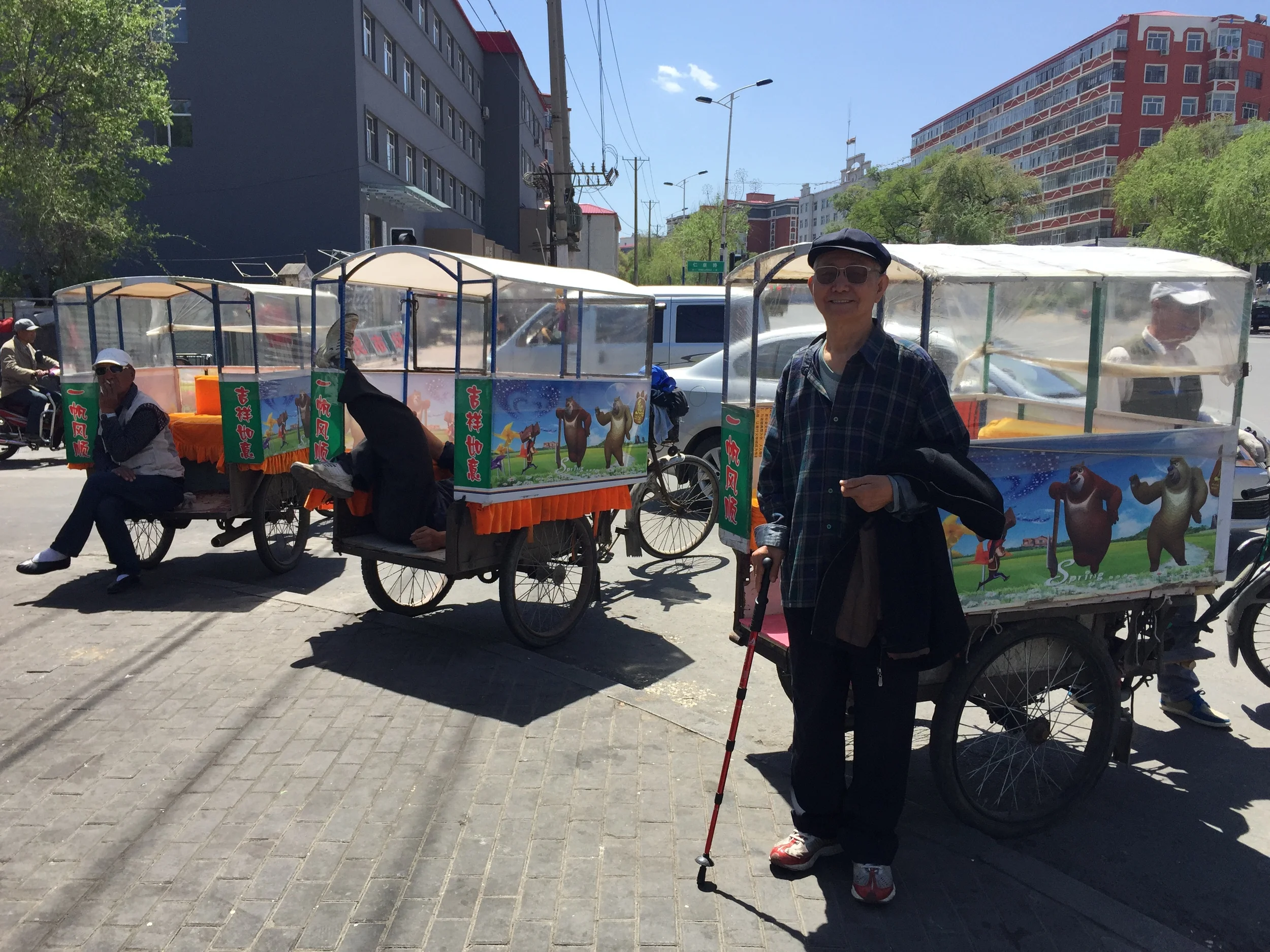The older Dr. Liu in front of some rickshaws.