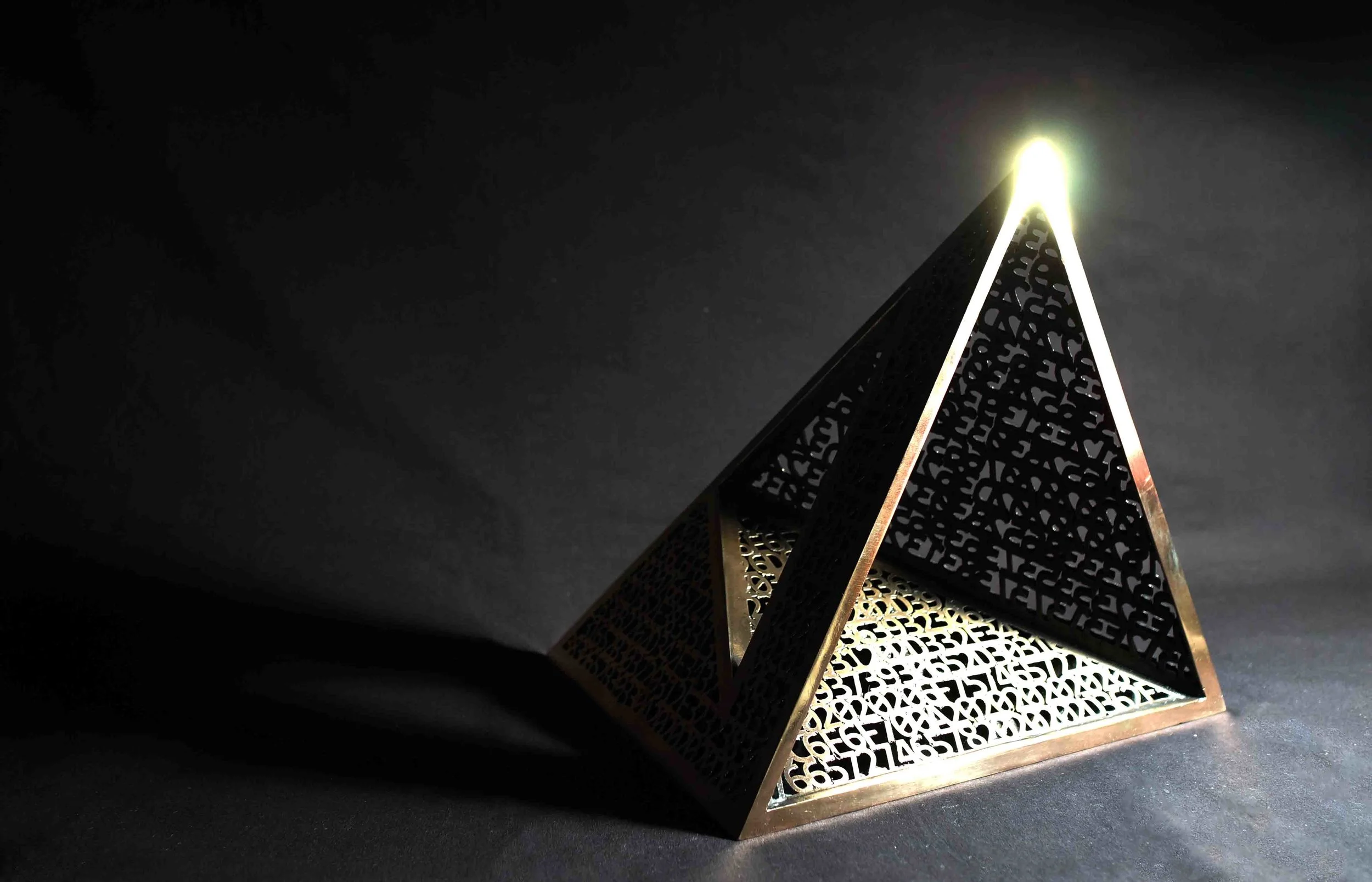 SPACE TRIANGLE 2016 cast bronze 12 x 12 x 12 in The Reverse Abstraction series begins with a simple premise: that humans and computers perceive the world through different languages, and what is concrete for one is abstract for the other. The objects and shapes so familiar in human art can be neither perceived nor conceived by computers in their original form. Likewise, the codes that are so familiar to a computer are merely scattered symbols to human sensibility. The Reverse Abstraction series attempts to bridge the gap by constructing traditional objects in dual forms: as the classical object and as the hexadecimal and binary codes that represent them. Thus, abstraction becomes material, the meanings for humans and computers are united, and the duality is resolved. TL;DR The text is code. If a computer were to read that code it would see the object you are seeing. This is art you both can enjoy.