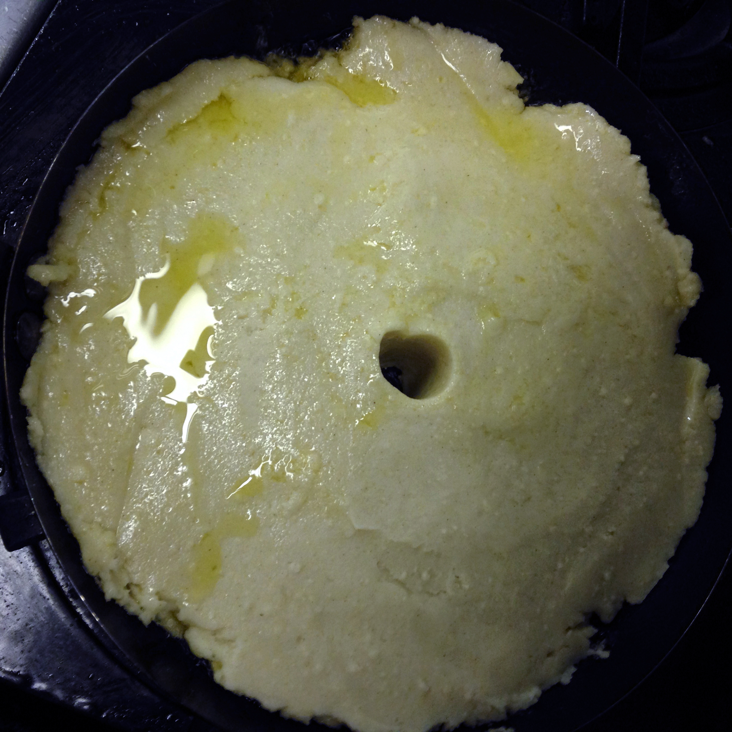 The corn flour "pizza" shortly after it went into the pan, a steam vent was poked with the handle of a wooden spoon