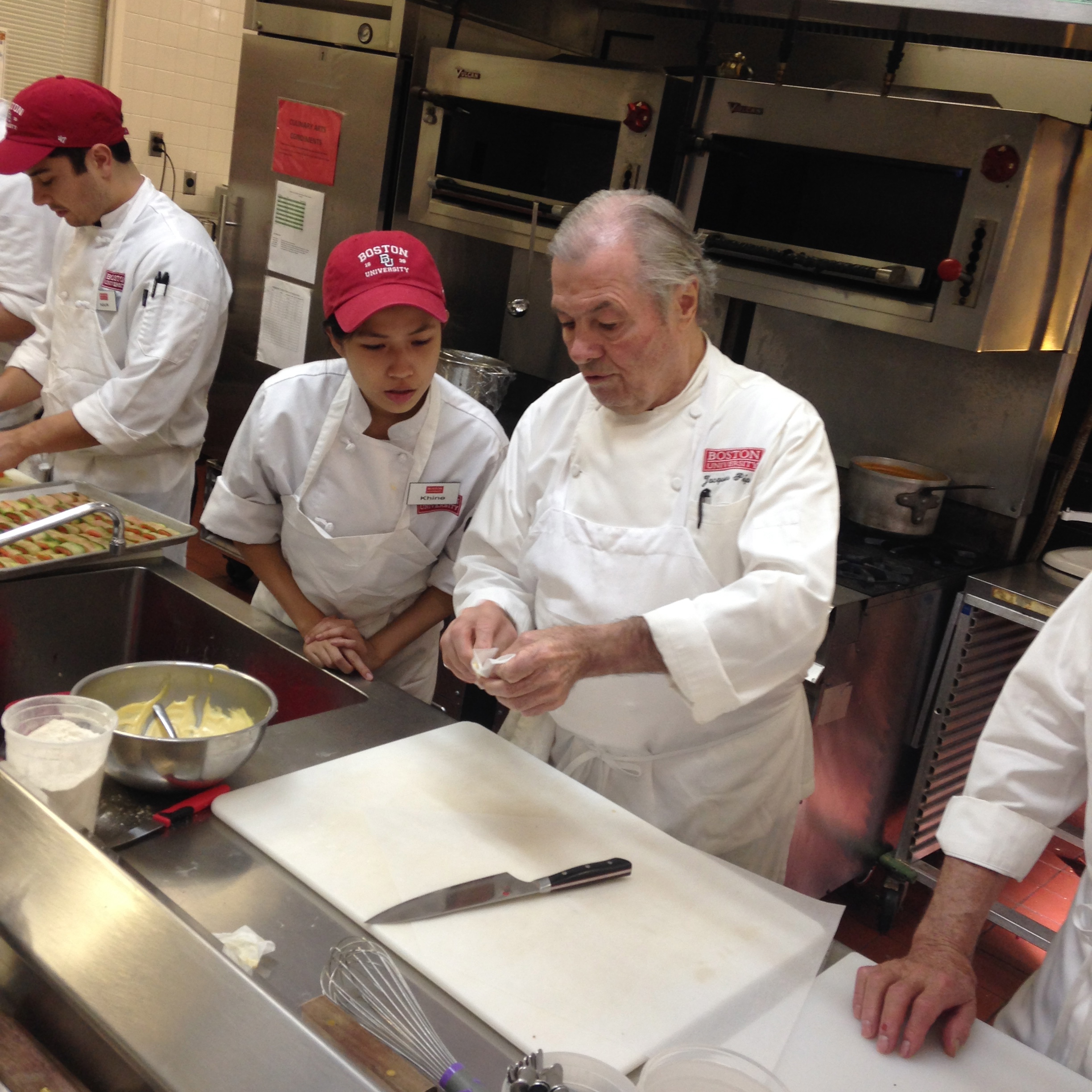 Jacques teaches a student how to make a parchment pastry bag