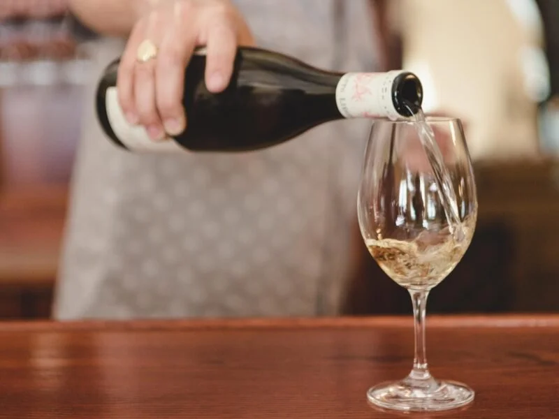 Person pouring rosé wine into a glass at a bar or restaurant