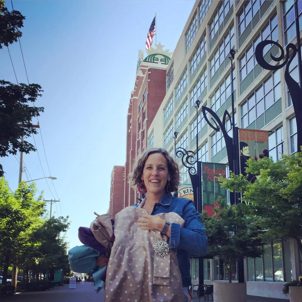 (May 28, 2015) Megan donates her dress during The Dress Projects Seattle Dress Drive. Volunteer, Genia Cayce holds the dress and other donated dresses outside of Starbucks headquarters, where The Dress Project team shared our vision with local Seattle socially-minded business leaders.