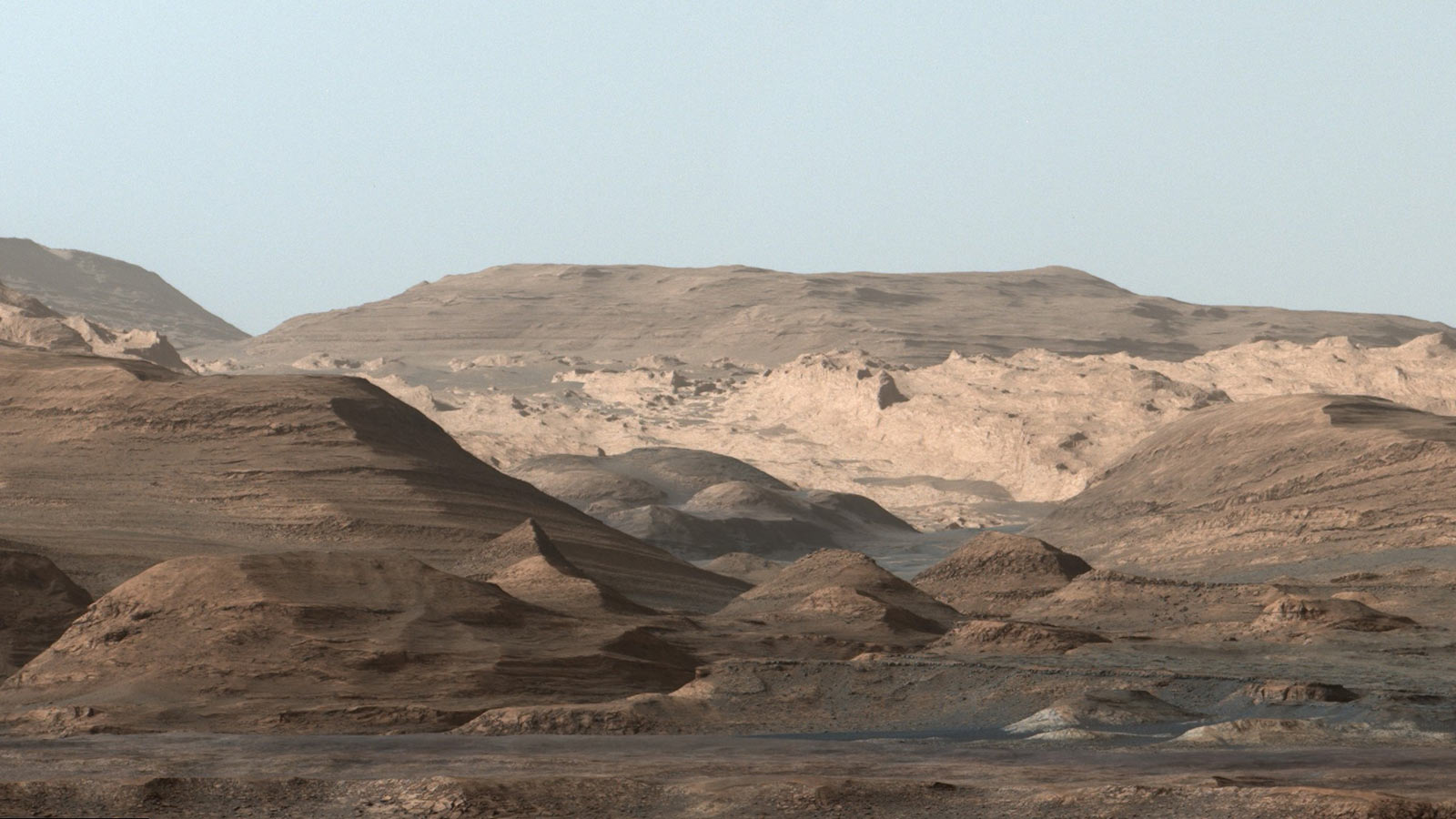 This composite image looking toward the higher regions of Mount Sharp was taken on September 9, 2015, by NASA's Curiosity rover. In the foreground -- about 2 miles (3 kilometers) from the rover -- is a long ridge teeming with hematite, an iron oxide. Credits: NASA/JPL-Caltech/MSSS