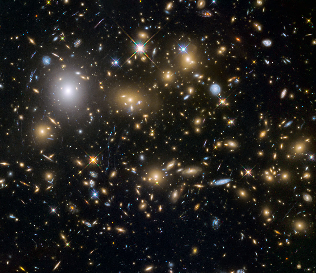 This image from the NASA/ESA Hubble Space Telescope shows the galaxy cluster MACSJ0717.5+3745. This is one of six being studied by the Hubble Frontier Fields programme, which together have produced the deepest images of gravitational lensing ever made. Due to the huge mass of the cluster it is bending the light of background objects, acting as a magnifying lens. It is one of the most massive galaxy clusters known, and it is also the largest known gravitational lens. Of all of the galaxy clusters known and measured, MACS J0717 lenses the largest area of the sky. - Credit: NASA, ESA and the HST Frontier Fields team (STScI)