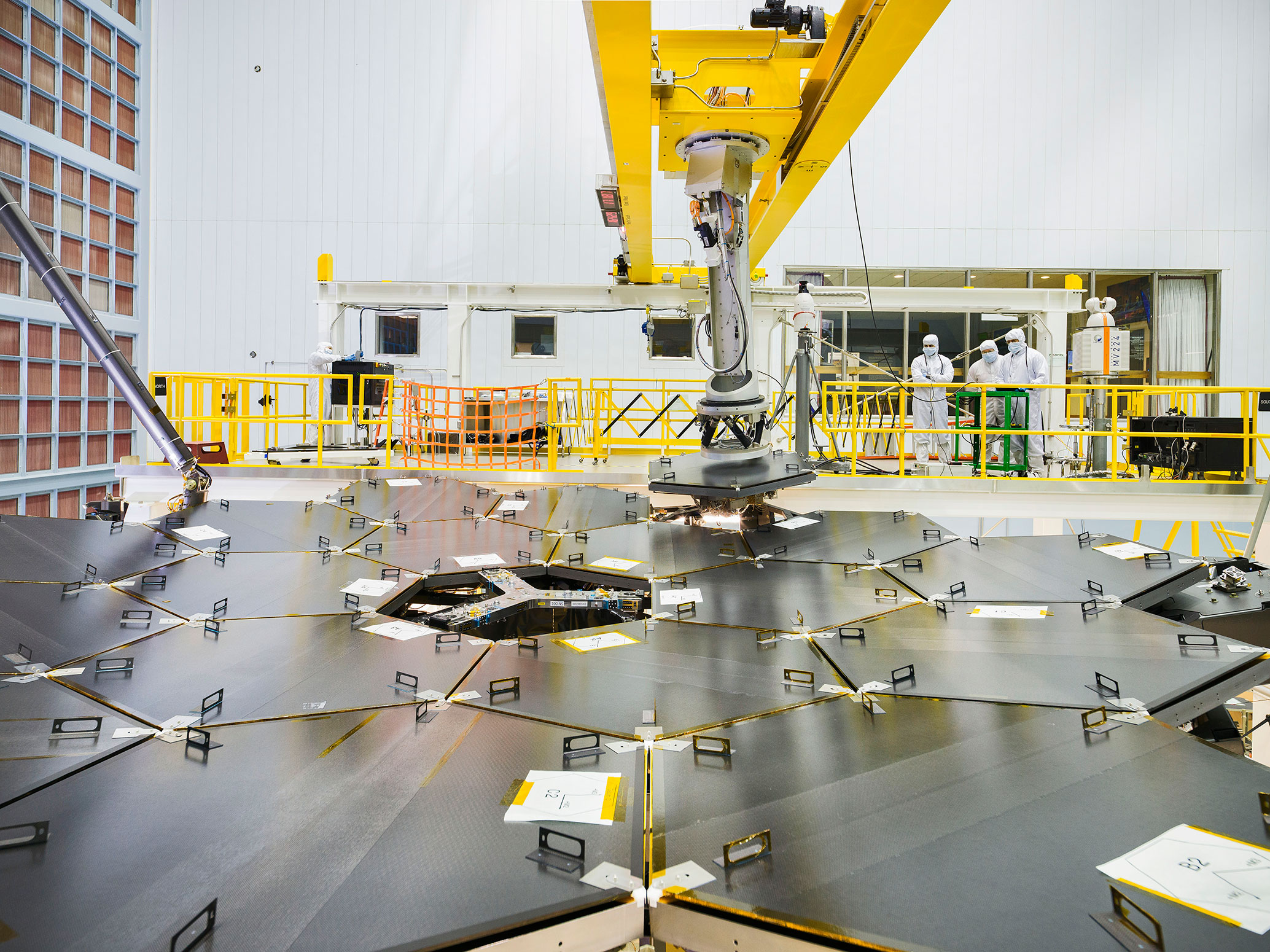 Inside a massive clean room at NASA's Goddard Space Flight Center in Greenbelt, Maryland the James Webb Space Telescope team used a robotic am to install the last of the telescope's 18 mirrors onto the telescope structure. - Image Credits: NASA/Chris Gunn