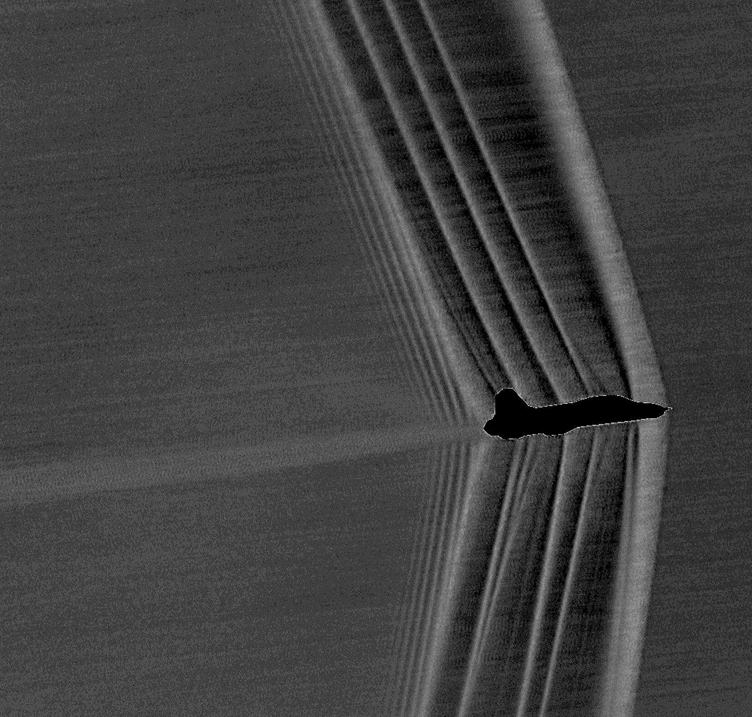 Shockwaves produced by a U.S. Air Force Test Pilot School T-38 banking at Mach 1.05 are captured by a new ground-operated camera and filter to study flow patterns and provide NASA engineers with methods of furthering research toward developing a soft “thump” in place of heavy sonic boom. - Image Credits: NASA