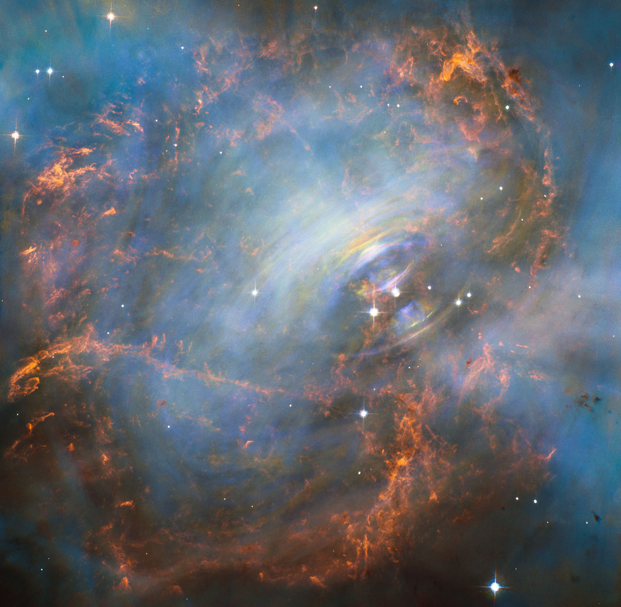 While many other images of the famous Crab Nebula have focused on the filaments in the outer part of the nebula, this image shows the very heart of the Crab Nebula including the central neutron star — it is the rightmost of the two bright stars near the centre of this image. The rapid motion of the material nearest to the central star is revealed by the subtle rainbow of colours in this time-lapse image, the rainbow effect being due to the movement of material over the time between one image and another. – Image Credit: NASA, ESA