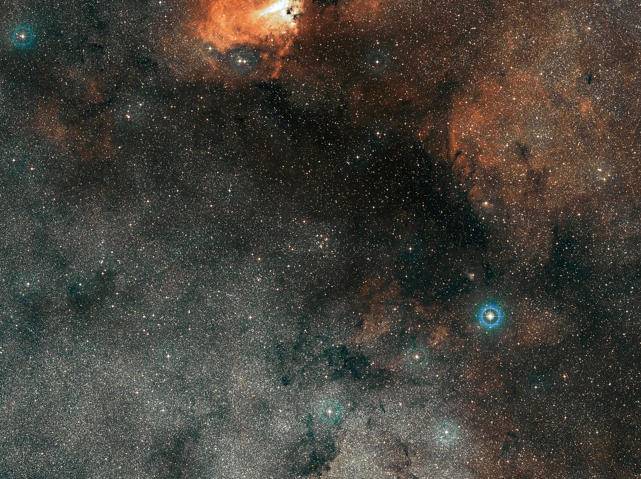 The small smattering of bright stars at the centre of this wide-field view is Messier 18, an open star cluster containing stars that formed together from the same massive cloud of gas and dust. This picture, which also shows part of the bright Omega Nebula (Messier 17) at the top, was created from images forming part of the Digitized Sky Survey 2. - Image Credit: ESO/Digitized Sky Survey 2. Acknowledgement: Davide De Martin