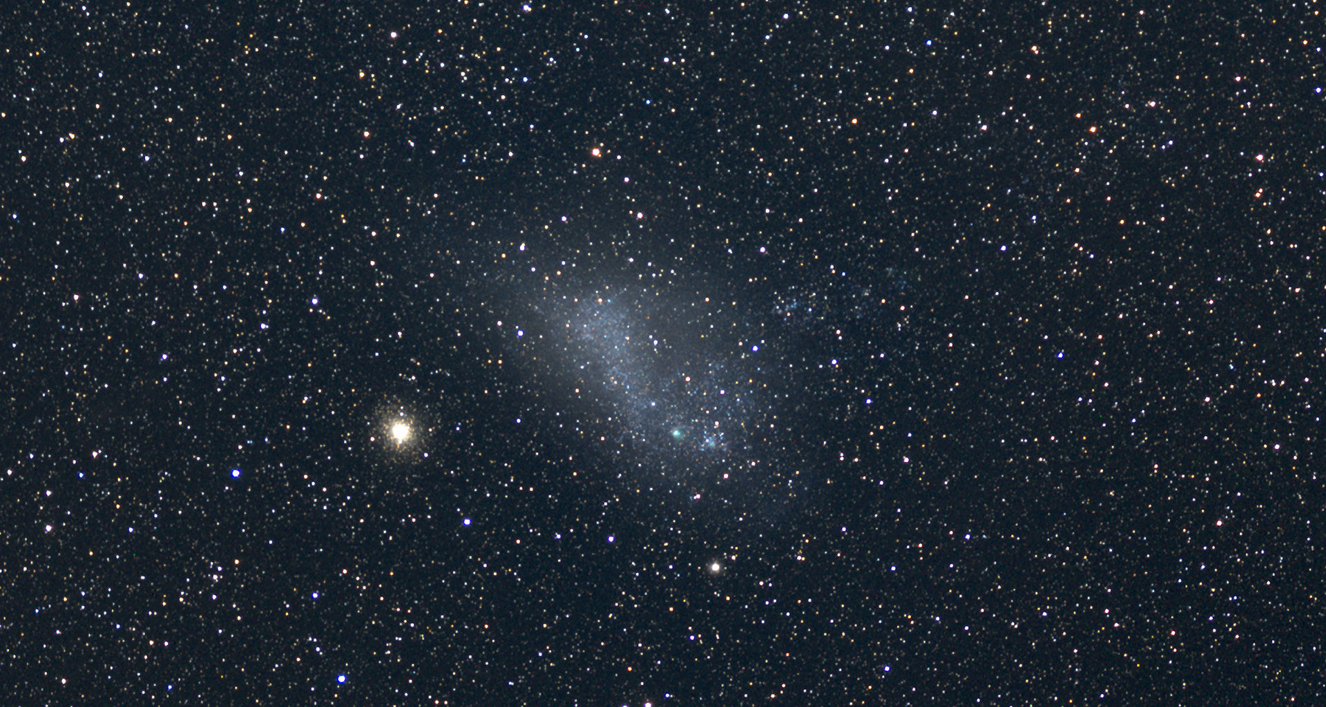 Visible light image of the Small Magellanic Cloud (SMC, at center), which is located about 200,000 light-years away and is the second-largest of the small satellite galaxies orbiting our Milky Way galaxy. The bright globular cluster 47 Tucanae (NGC 104) is visible at left and lies about 17,000 light-years away. – Image Credit: Credit: Axel Mellinger, Central Michigan University