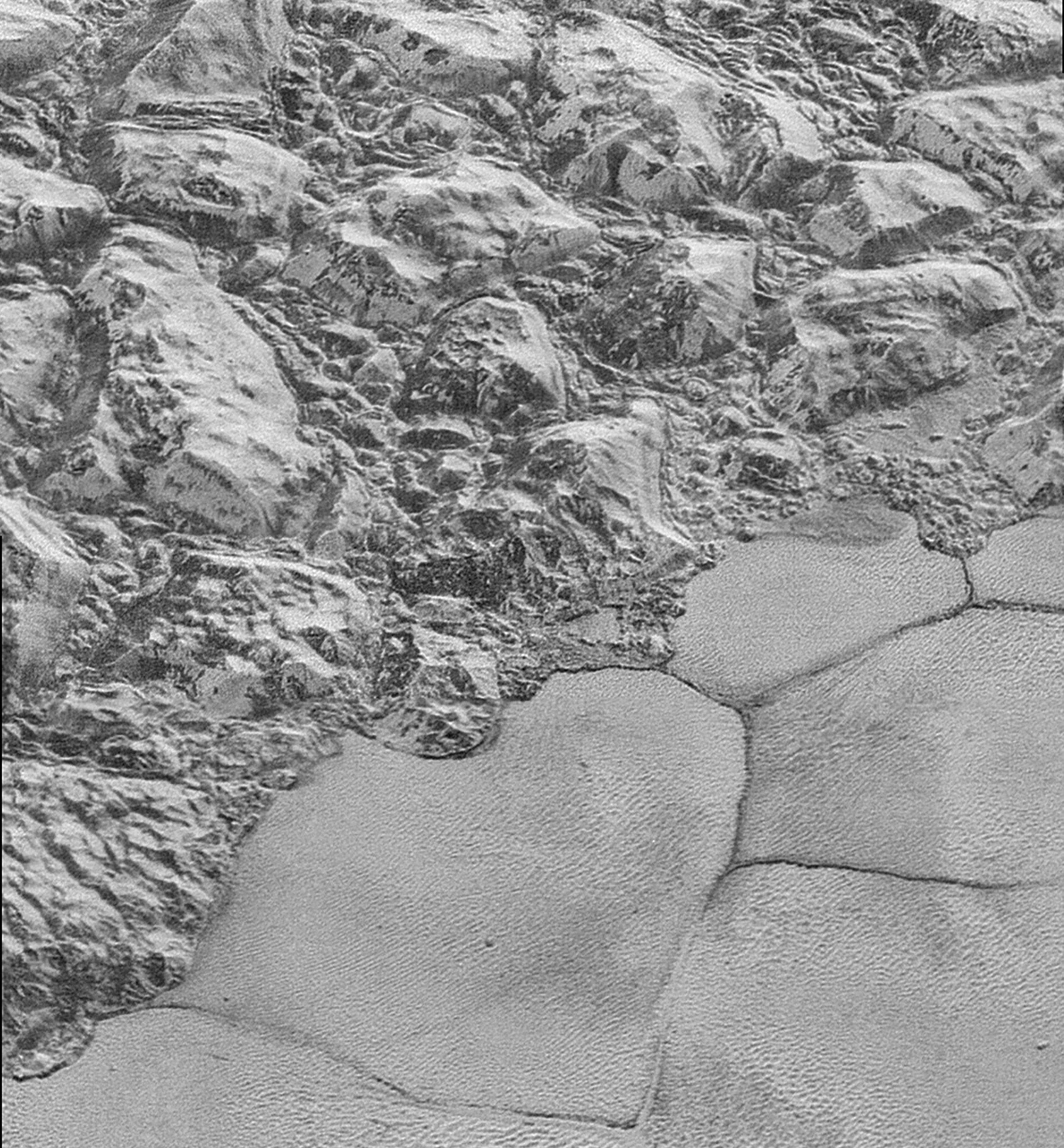The Mountainous Shoreline of Sputnik Planum on Pluto. Great blocks of Pluto’s water-ice crust appear jammed together in the informally named al-Idrisi mountains. Some mountain sides appear coated in dark material, while other sides are bright. - Image Credit: NASA/Johns Hopkins University Applied Physics Laboratory/Southwest Research Institute.