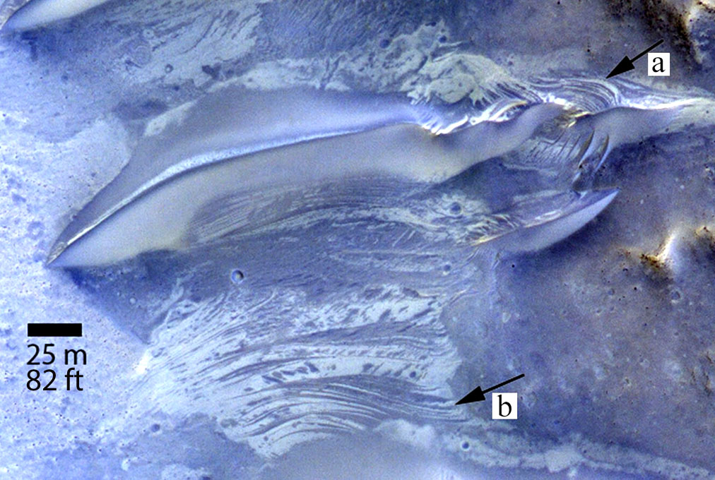 Striations exposed on the surface between Martian sand dunes (one pictured at top) in Lucaya Crater indicate fluctuating levels of salty groundwater. At “a” we see possible cross beds which are tilted layers of sand within larger layers deposited by wind or water. At b, dark and light strata are similar to that exposed in the dune at top and resemble the striations seen in the Namib Desert on Earth. The photo was taken by NASA’s Mars Reconnaissance Orbiter in infrared, red and blue light. - Image Credit: NASA/JPL-Caltech