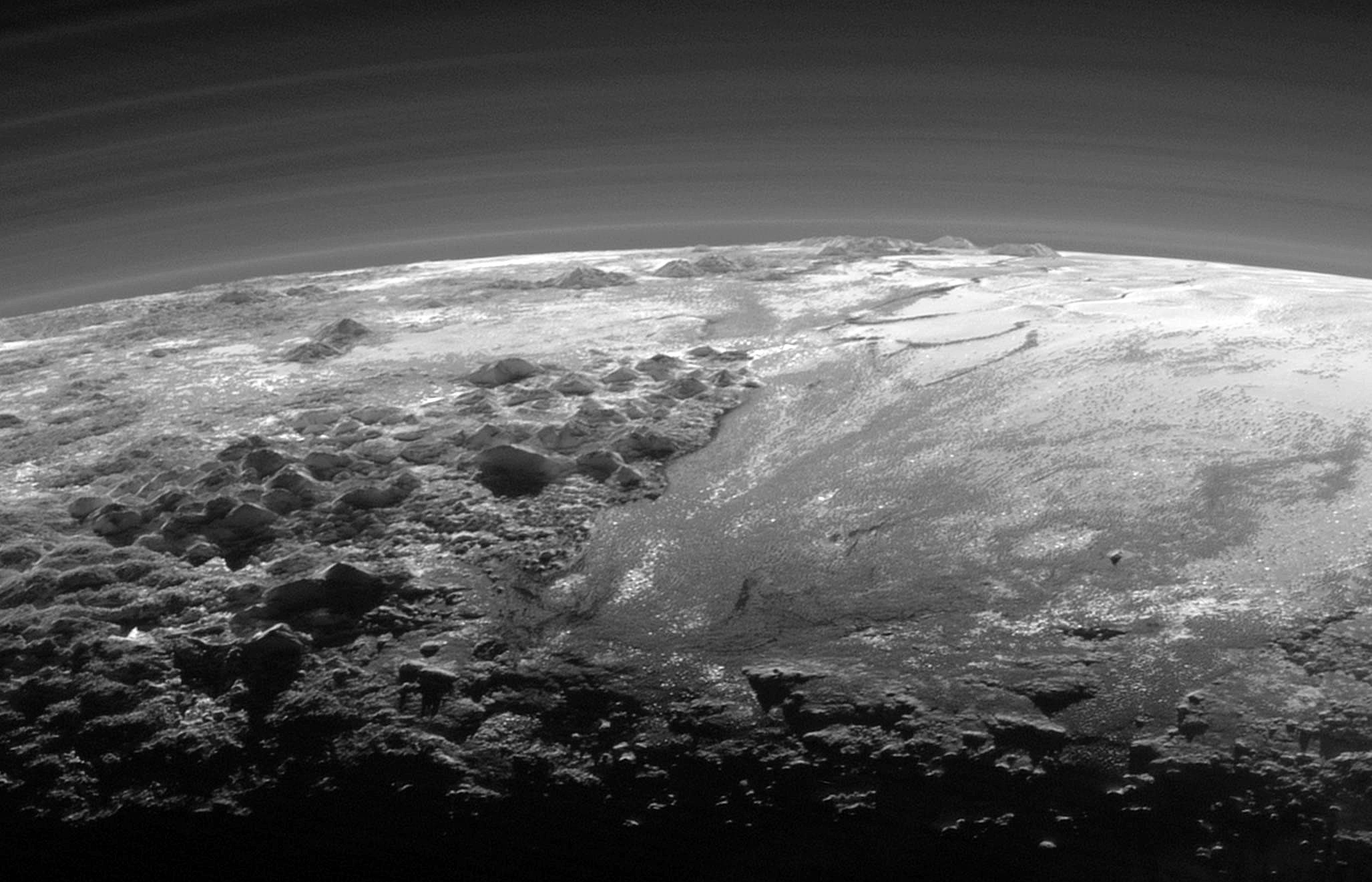 Haze with multiple layers in the atmosphere of Pluto. Part of the plain Sputnik Planitia with nearby mountains is seen below. Photo by New Horizons, taken 15 min after the closest approach to Pluto. - Image Credit: NASA/JHUAPL/SwRI