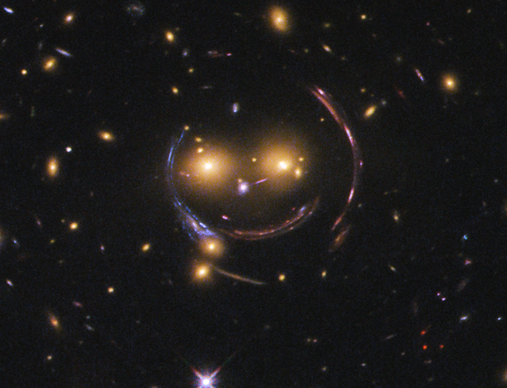 Dark matter is likely to be causing the arcs seen around the central galaxies in this image, making a smiling face.- Image Credit: NASA/ESA, CC BY-SA